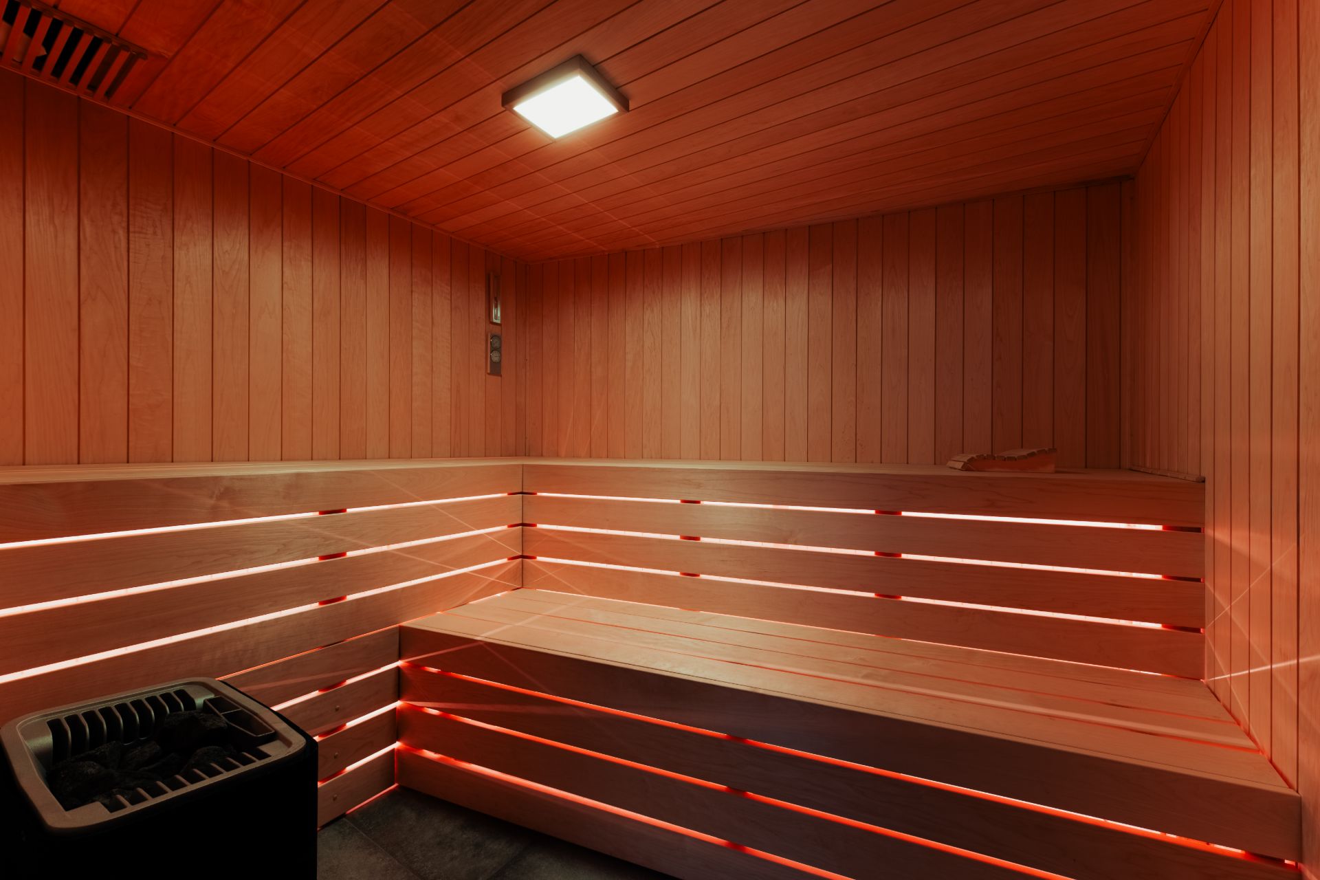 Innenansicht einer privaten Sauna mit Holzbänken und indirekter Beleuchtung.