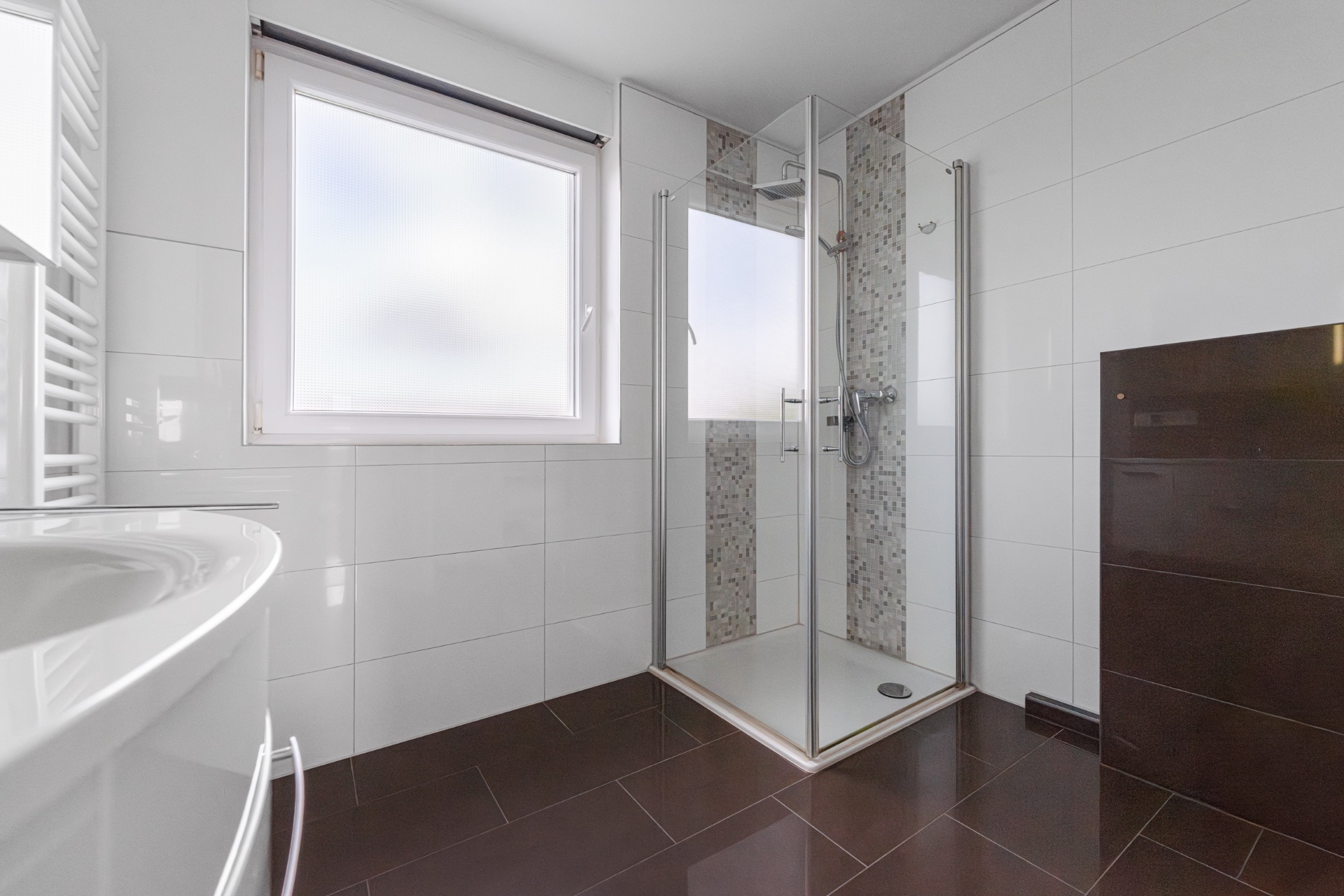 Modernes Bad mit großer Fensterfront, Dusche mit Glaswänden und dunklem Fliesenboden.