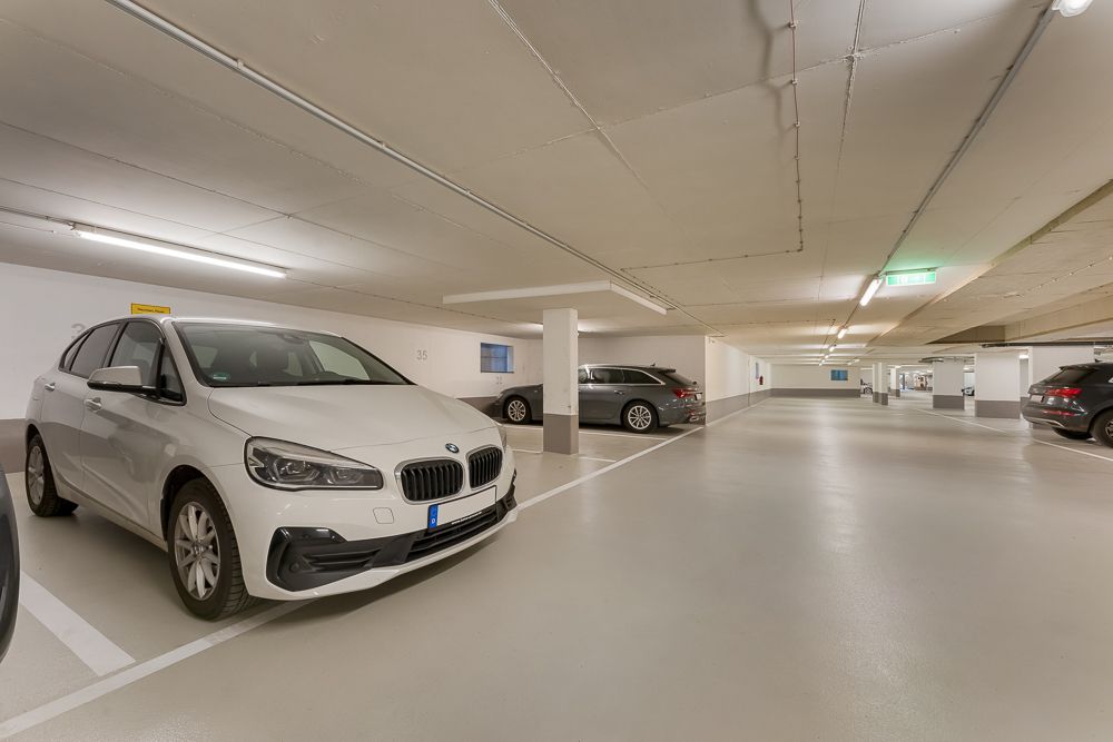 Tiefgarage mit mehreren geparkten Autos auf markierten Stellplätzen.