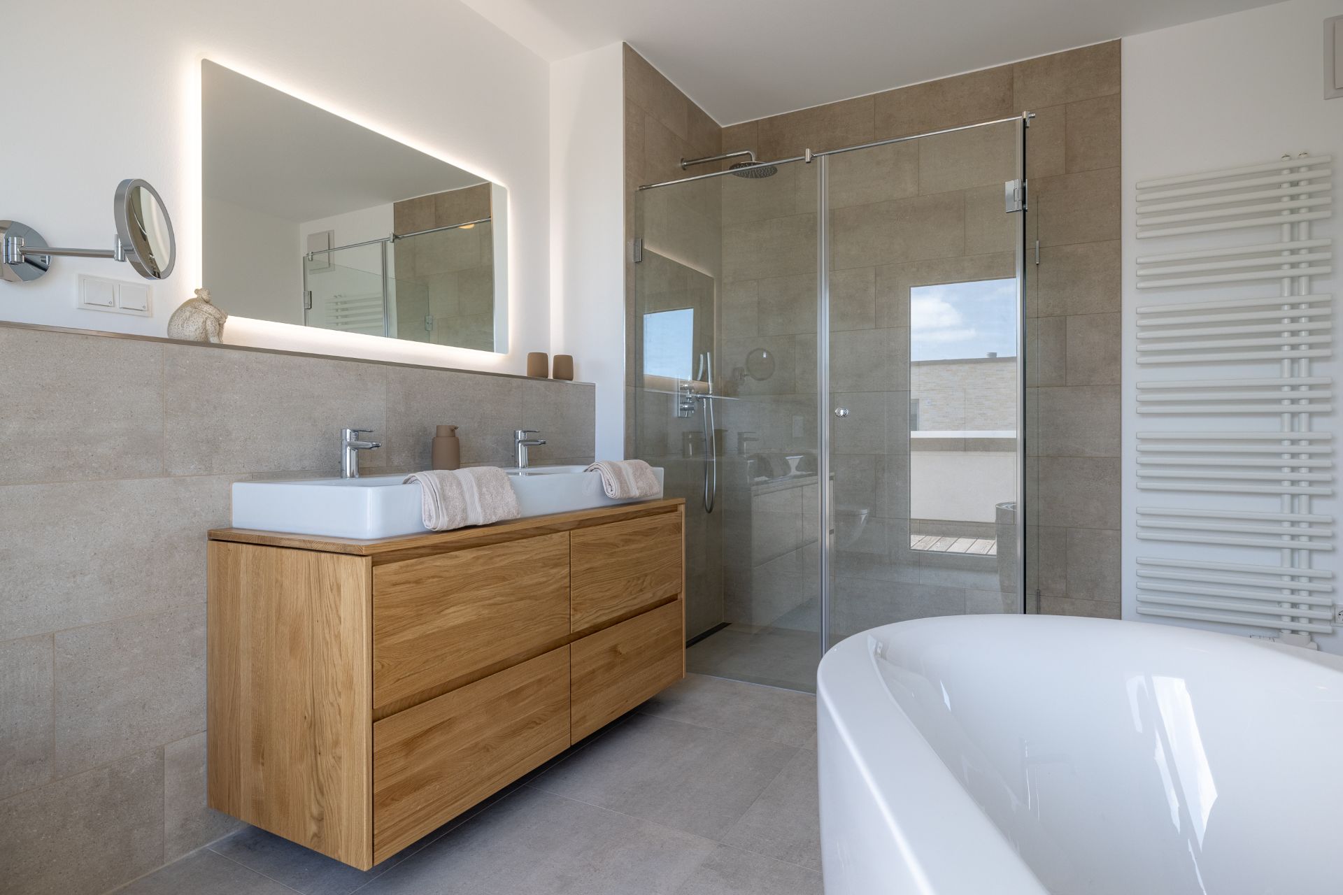 Modernes Badezimmer mit Doppelwaschbecken, Holzschrank, großer Dusche und freistehender Badewanne.