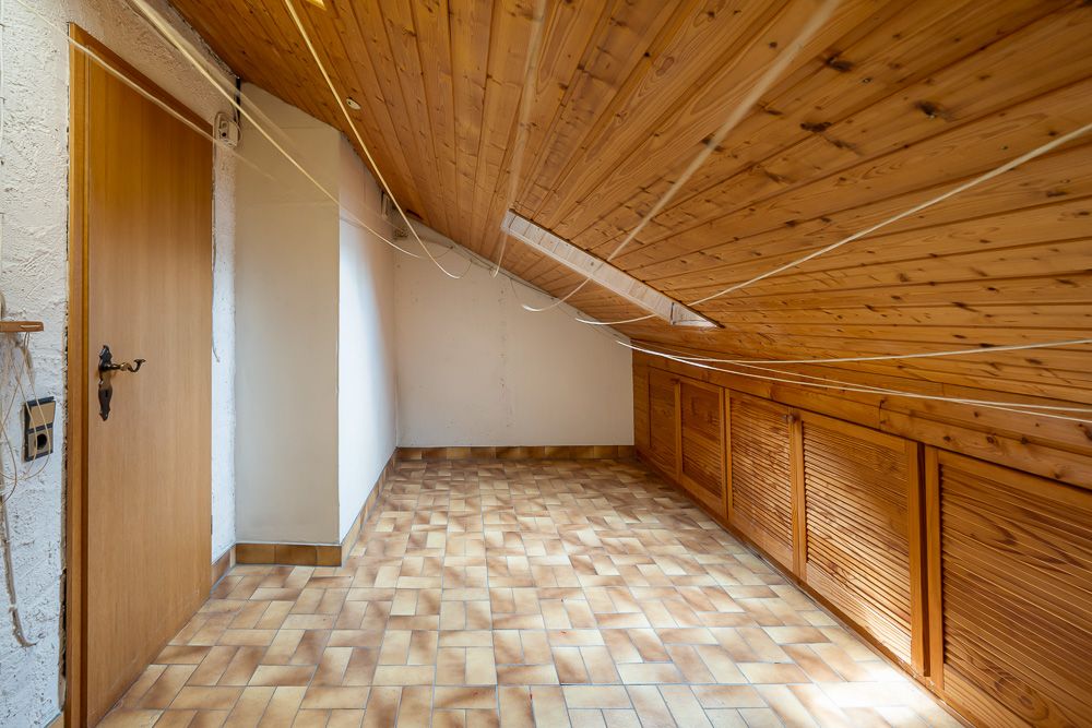 Kleiner Dachbodenraum mit Holzdecke, Dachfenster und gefliesten Boden.