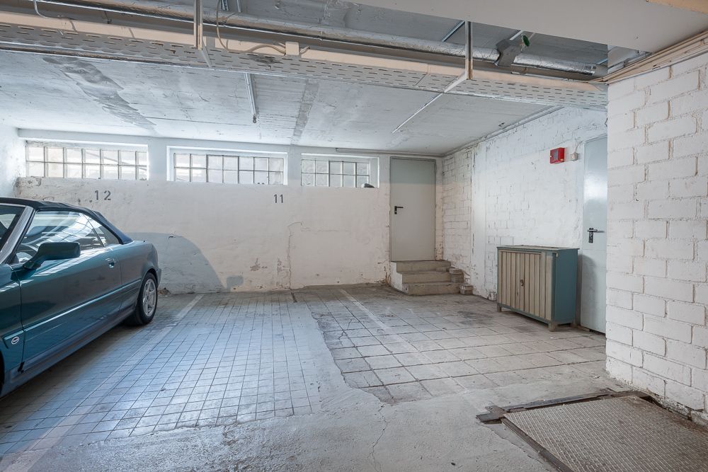 Heller Garagenplatz mit Autostellplatz, weißen Wänden und einem kleinen Schrank an der Seite.