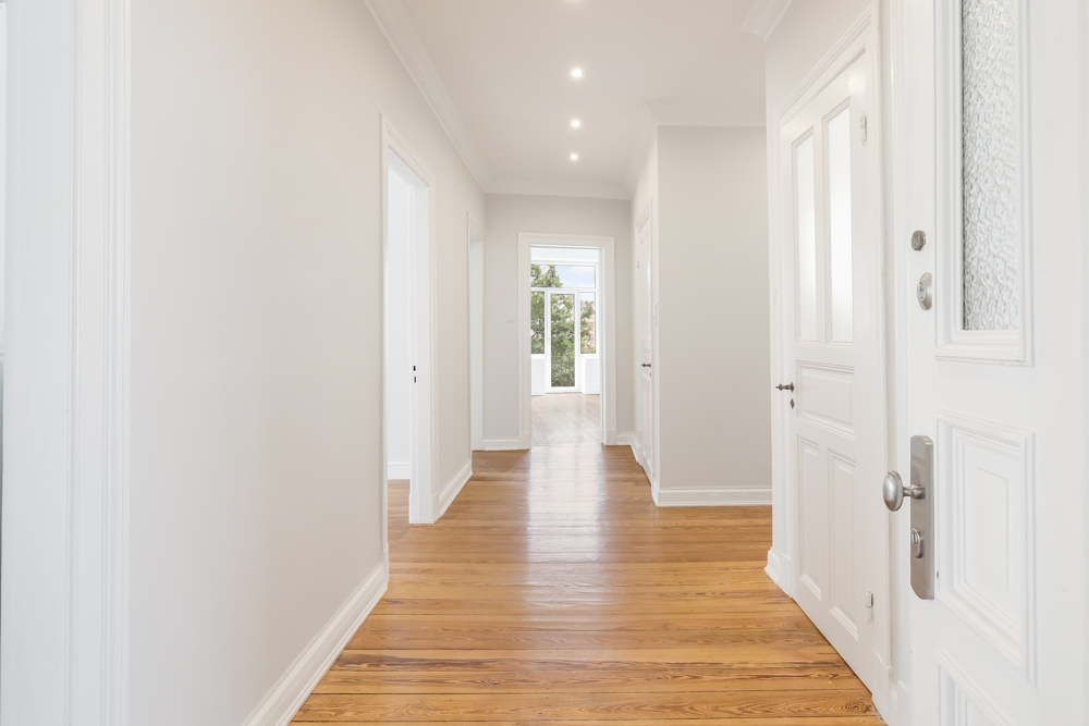 Heller Flur mit Holzboden, weißen Wänden und mehreren Türen in einem Wohnhaus.