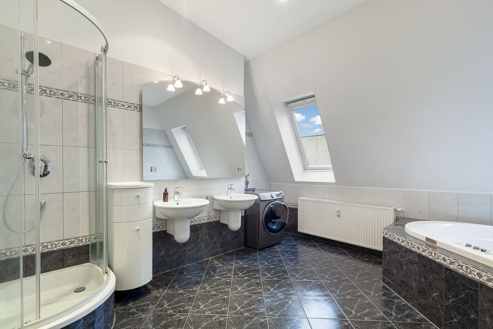 Modernes Bad mit Dusche, Badewanne, Doppelwaschbecken, Waschmaschine und Dachfenster.