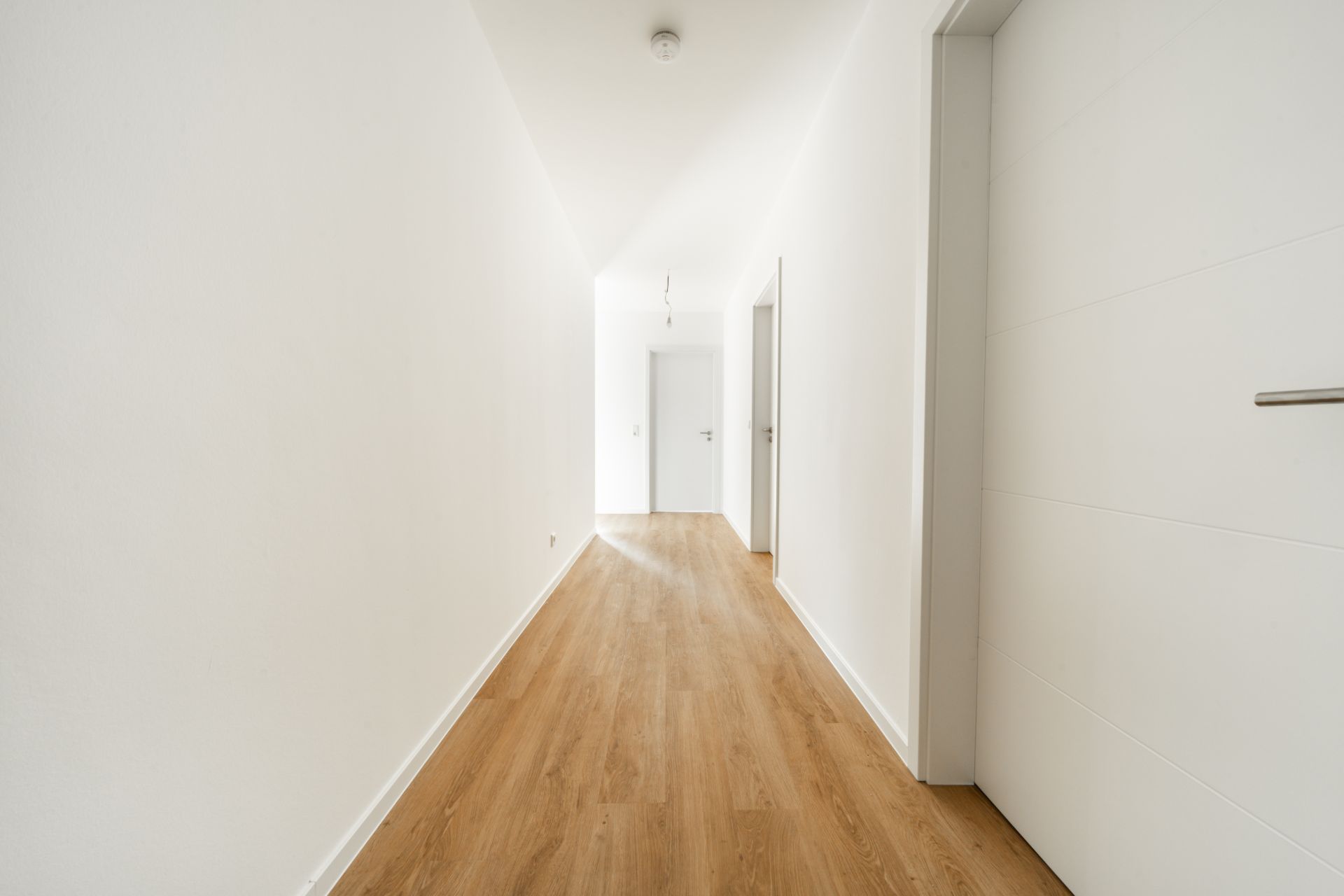 Heller Flur mit Holzboden und weißen Türen in einer Wohnung.