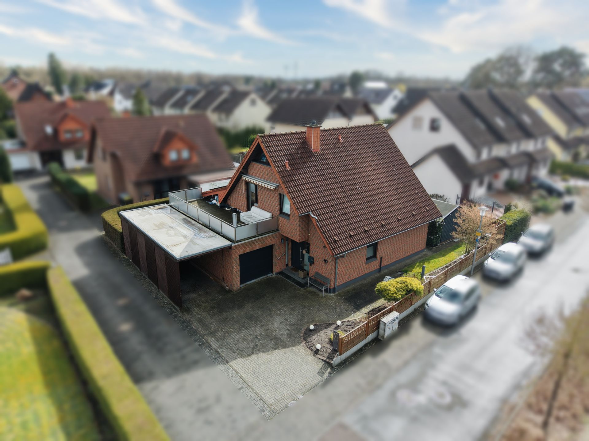 Backstein-Einfamilienhaus mit Satteldach, Carport, Terrasse und kleinem Vorgarten in Wohnsiedlung.