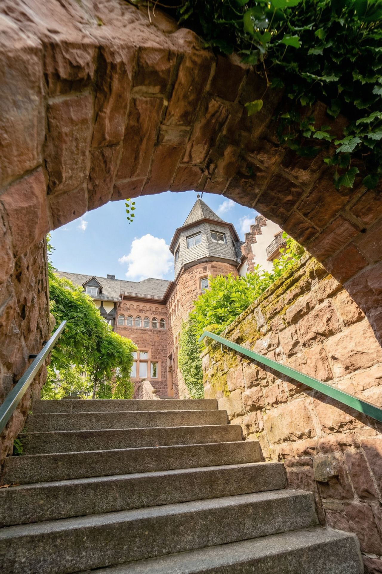 Steintreppe führt durch einen Torbogen zu einem historischen Wohngebäude mit Turm.