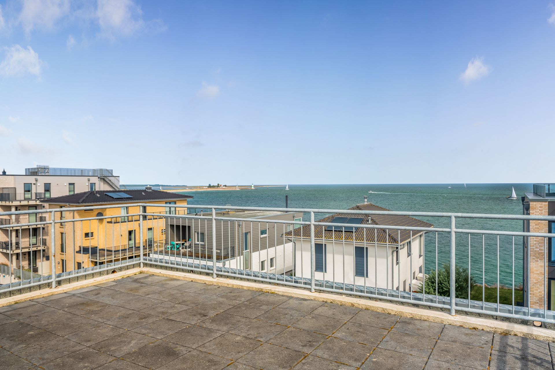 Große Dachterrasse mit Ausblick auf Meer und umliegende Wohnhäuser.