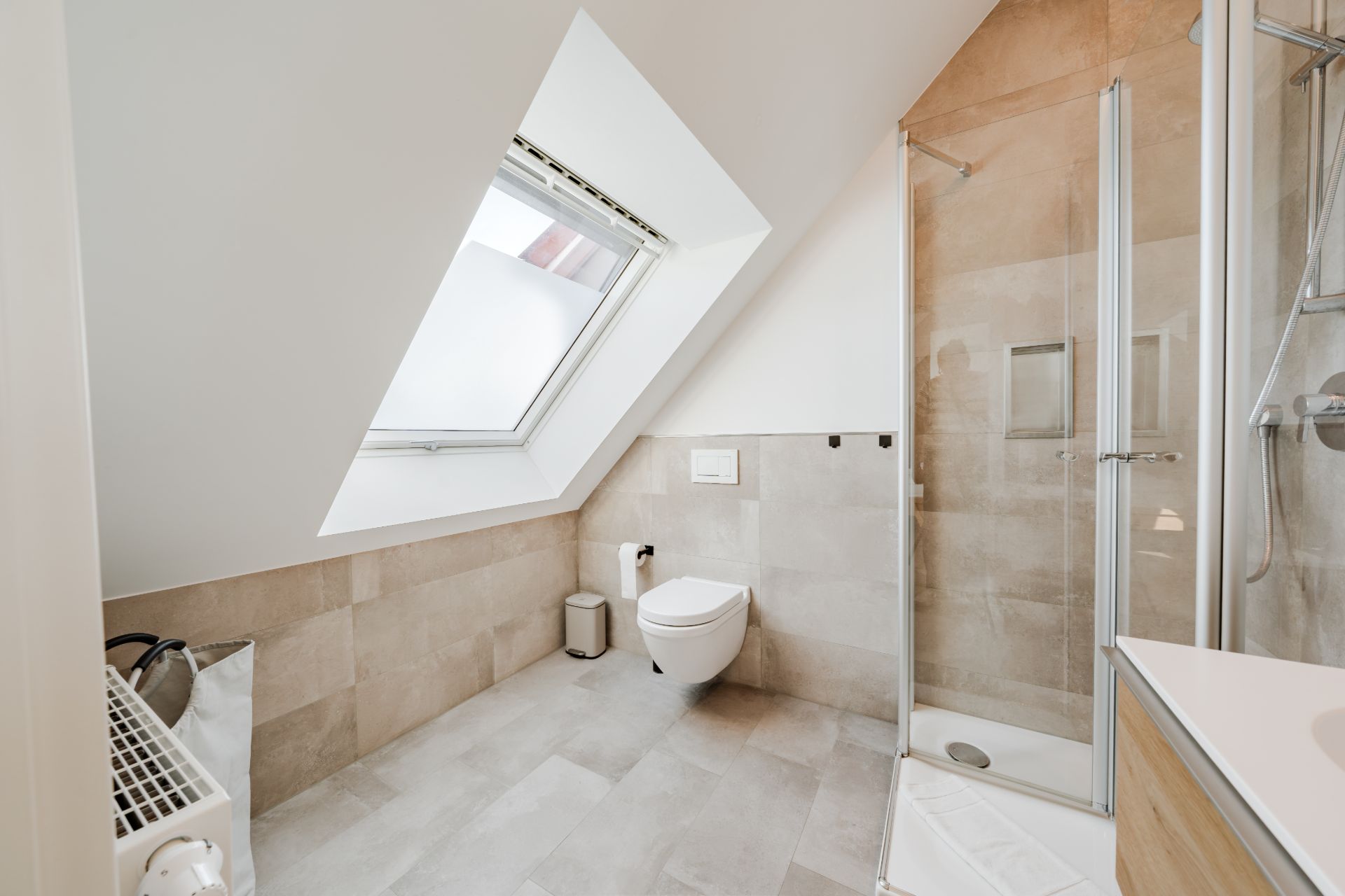 Modernes Badezimmer mit Dachfenster, Dusche, WC und Waschbecken.