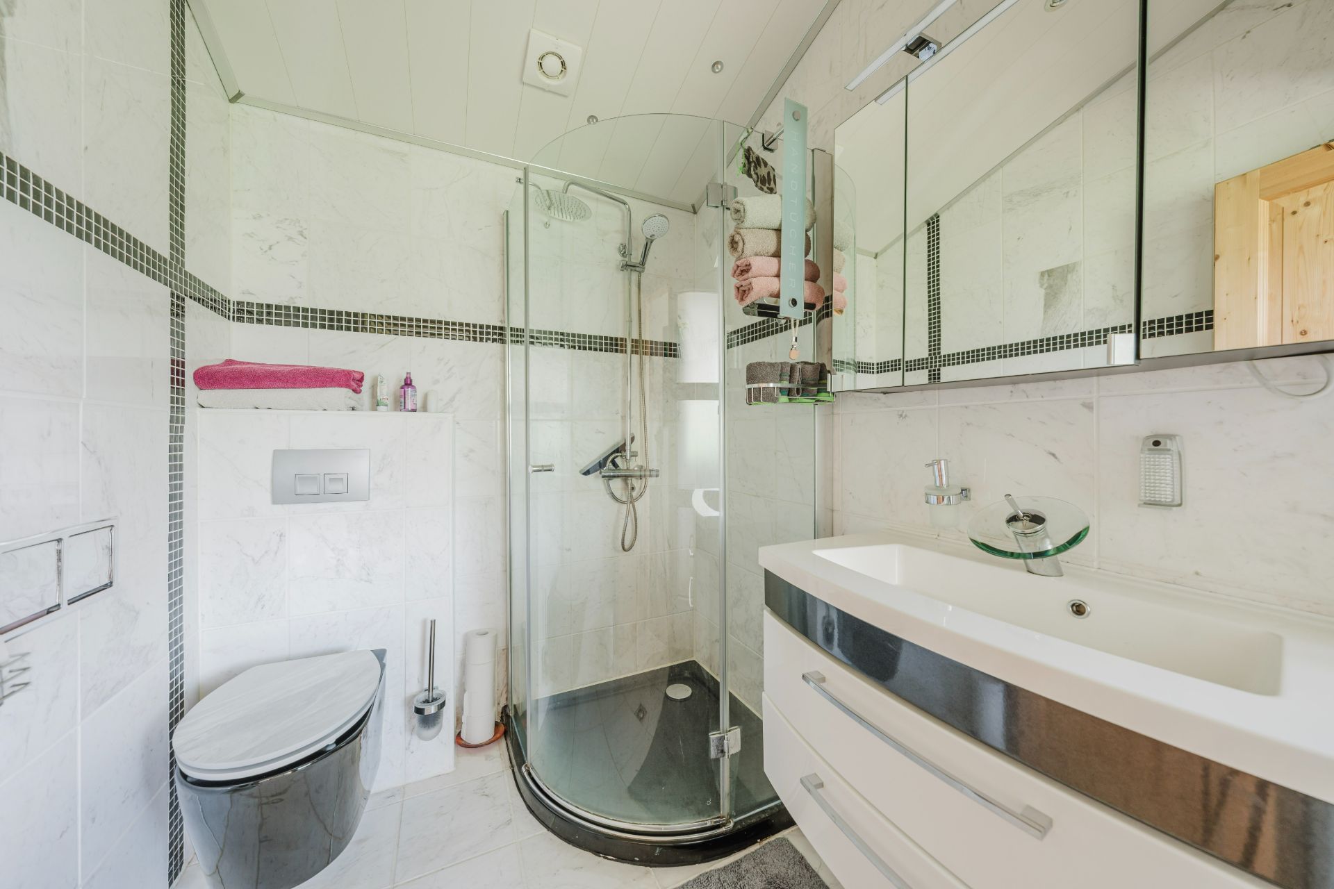 Modernes Badezimmer mit Dusche, WC, Waschbecken und großem Spiegel.