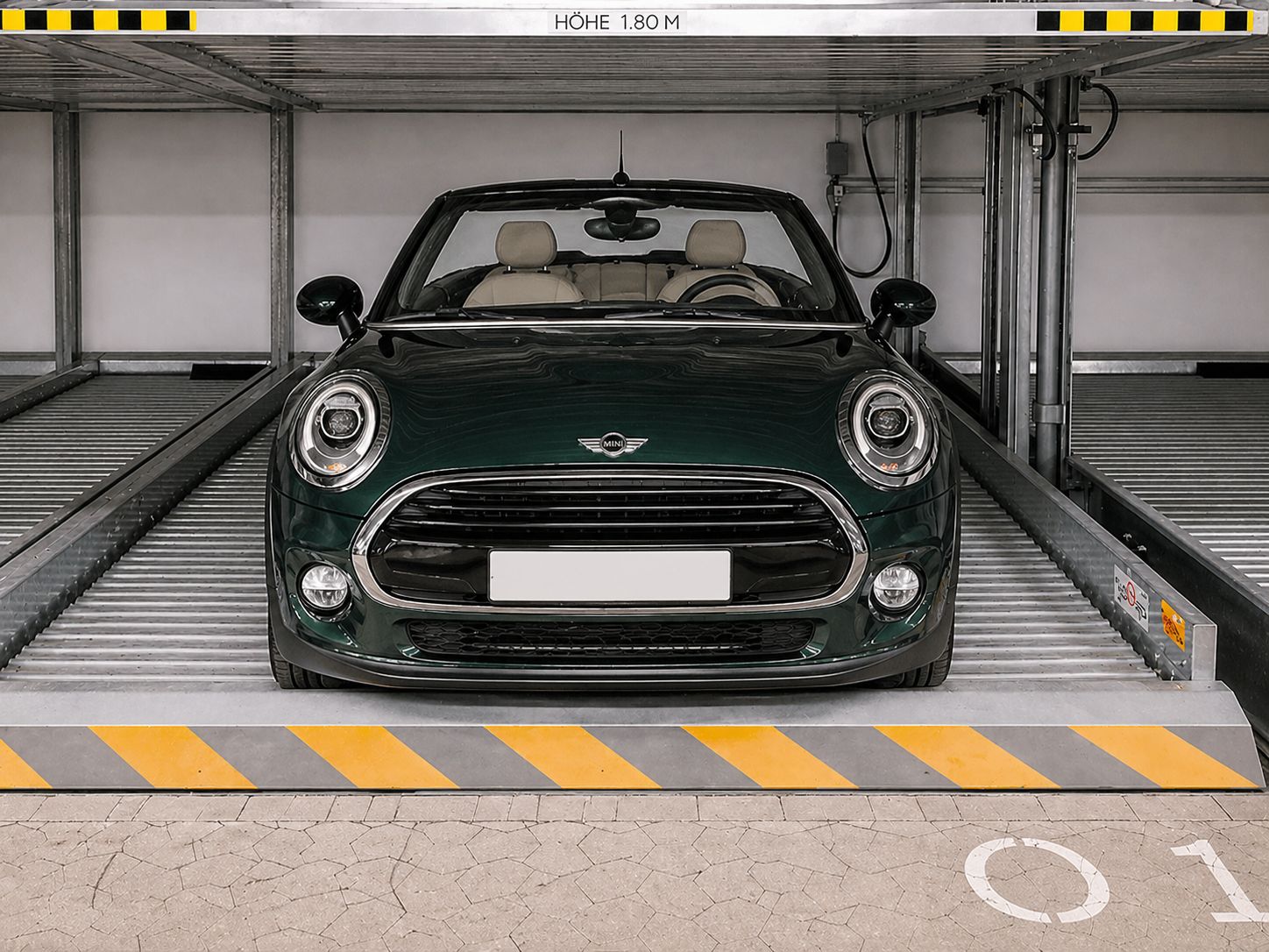 Ein grünes Auto steht in einer Tiefgaragenstellplatz mit gelb-schwarzer Markierung.