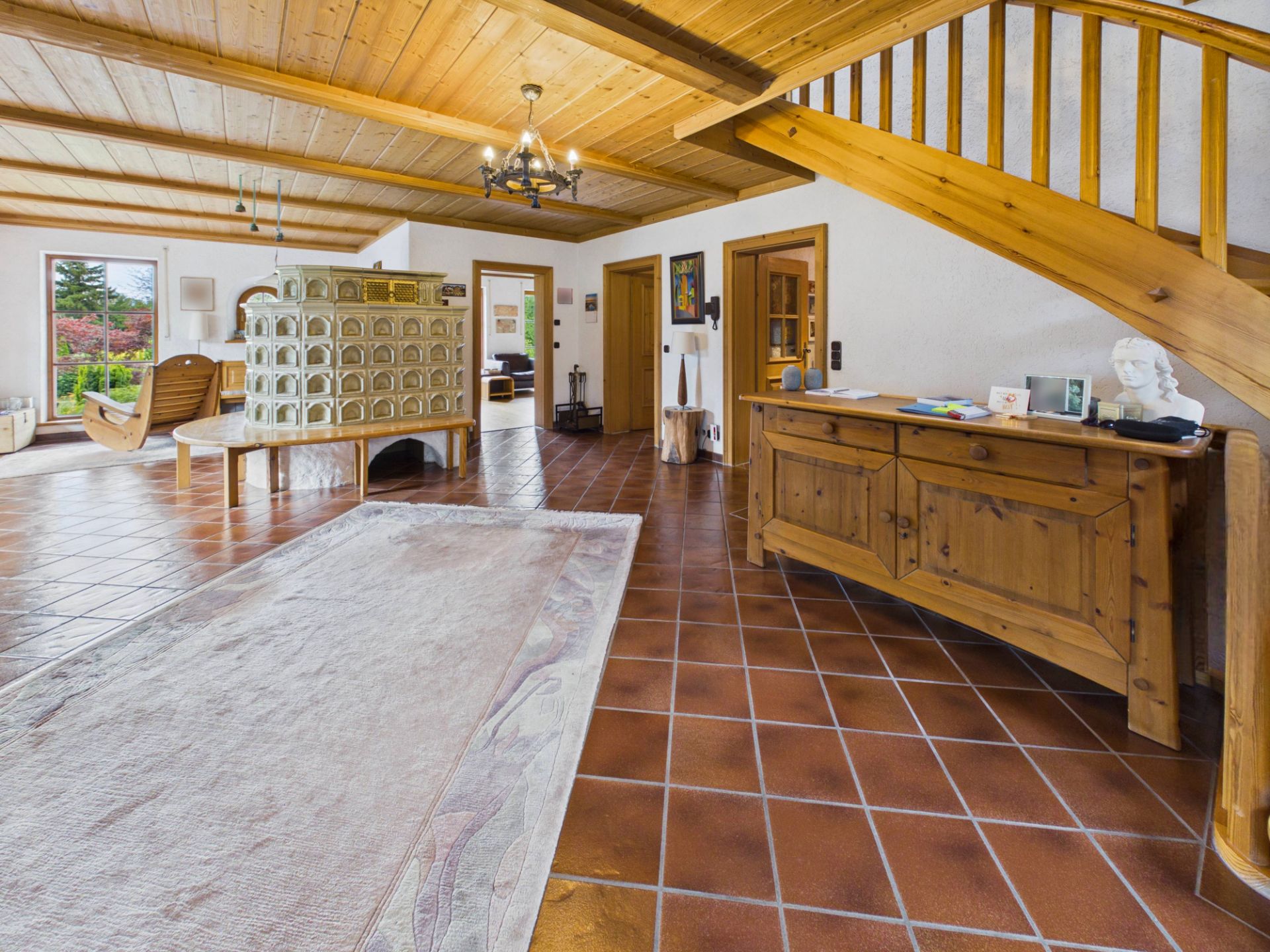 Heller Wohnbereich mit Holztreppe, Kaminofen, Teppich und Holzmöbeln.