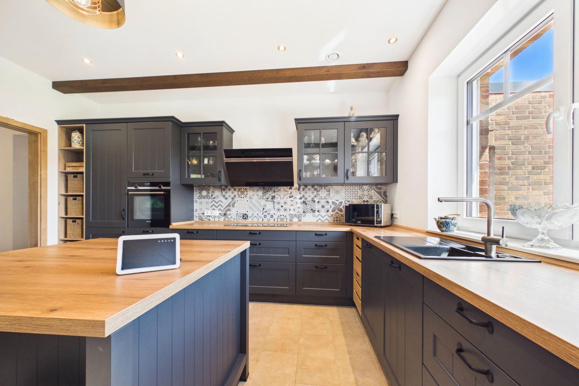 Moderne Küche mit dunklen Schränken, Holzarbeitsplatten, Fenster und Küchengeräten.
