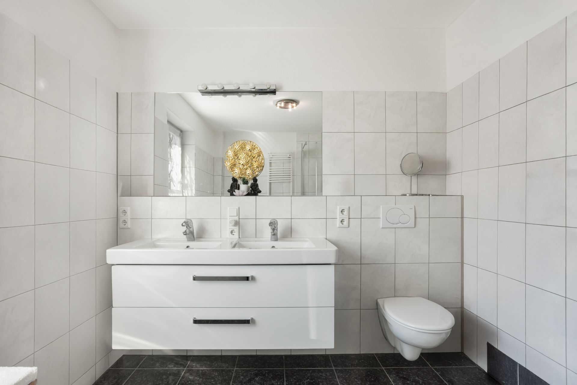 Modernes Badezimmer mit Doppelwaschbecken, großem Spiegel und wandhängender Toilette.