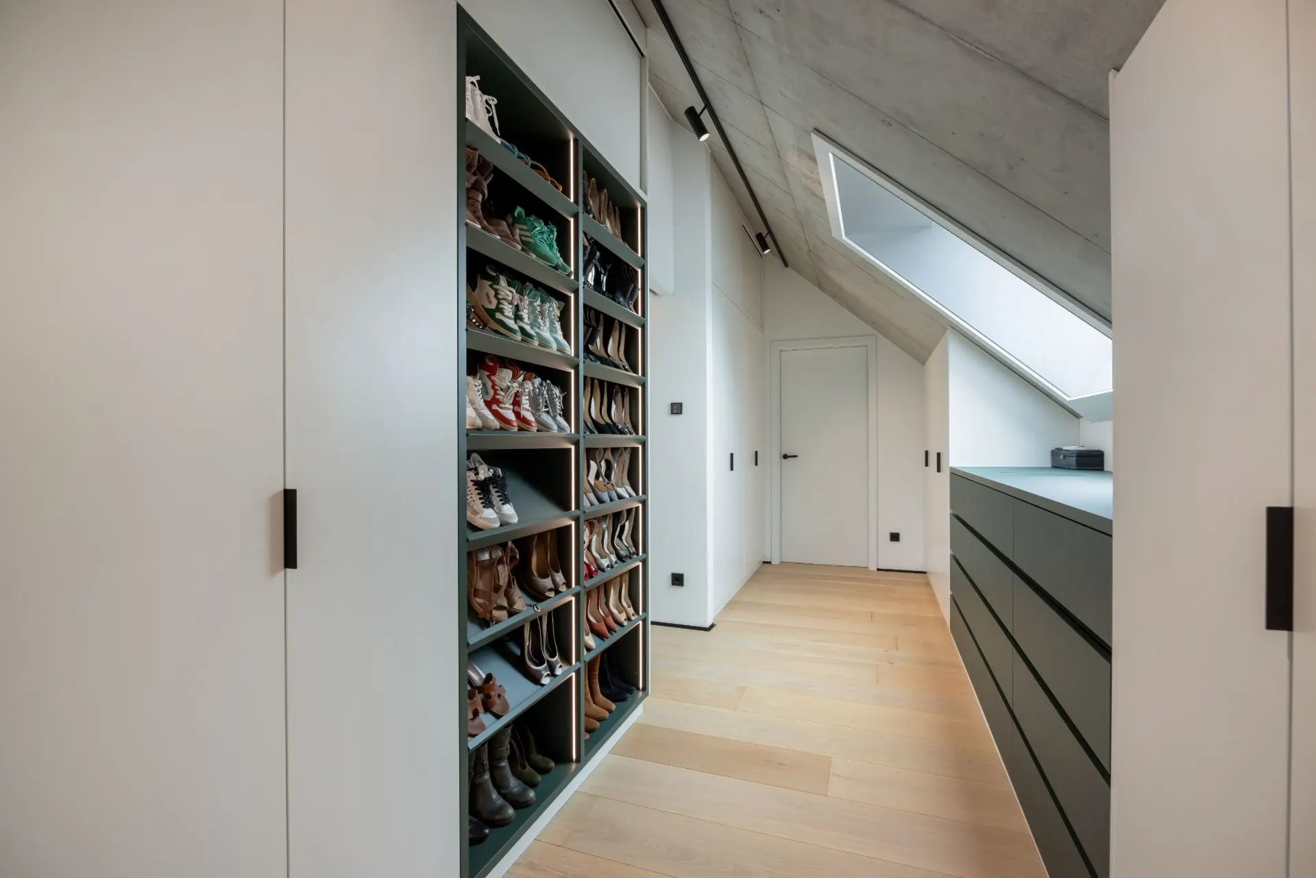 Schmaler Ankleideraum mit Schuhregal, Schubladen und Dachfenster.