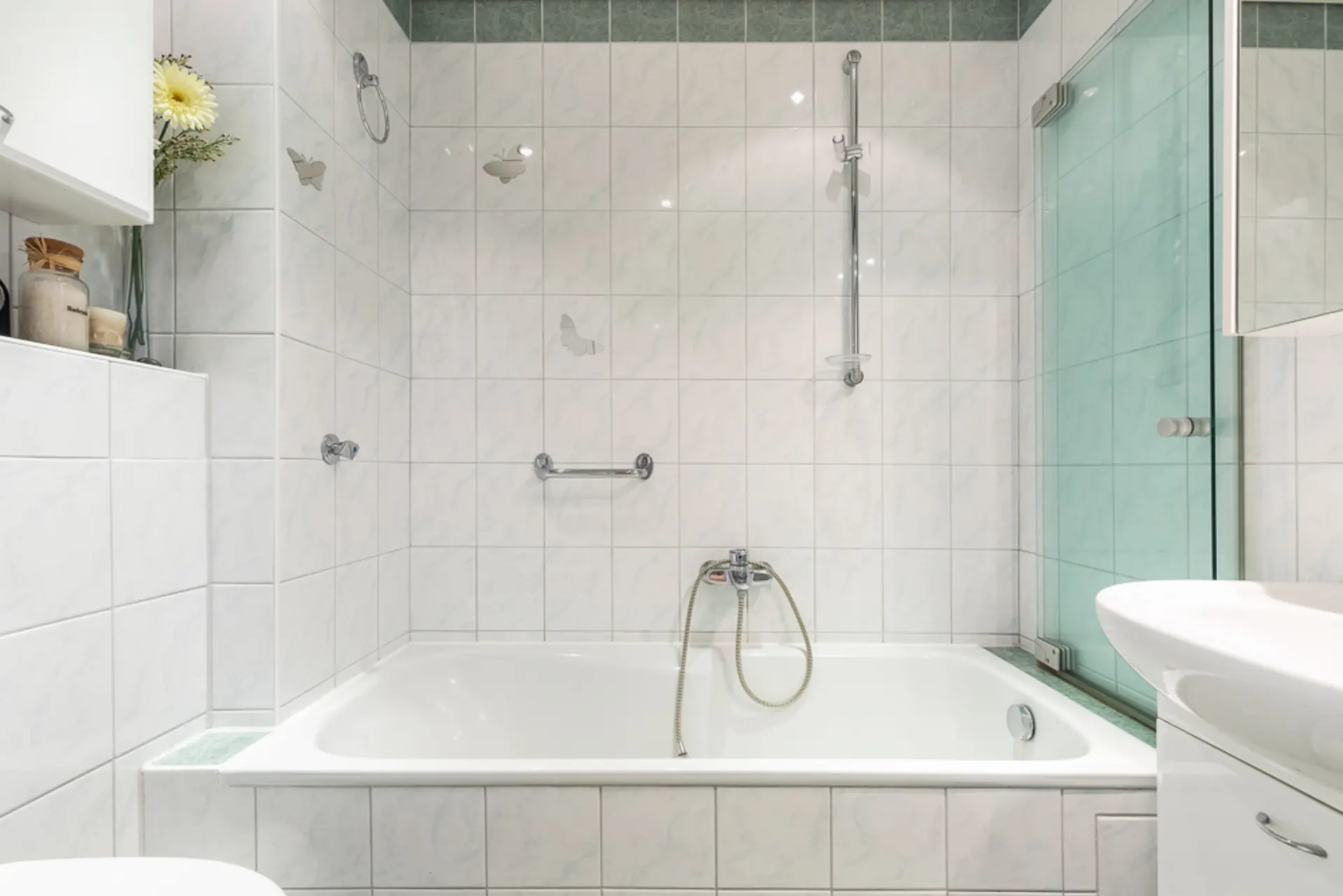 Modernes Badezimmer mit Badewanne, weißen Fliesen und Glasduschwand.