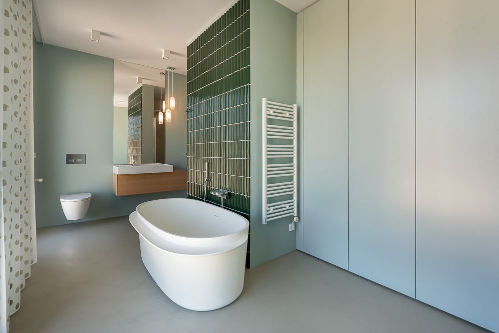Modernes Badezimmer mit freistehender Badewanne, Waschbecken, Wandtoilette und Handtuchheizkörper.