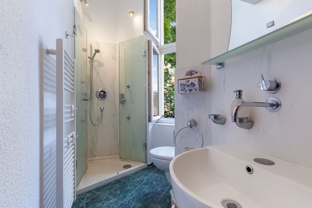 Modernes Badezimmer mit Dusche, Waschbecken, Toilette und offenem Fenster.