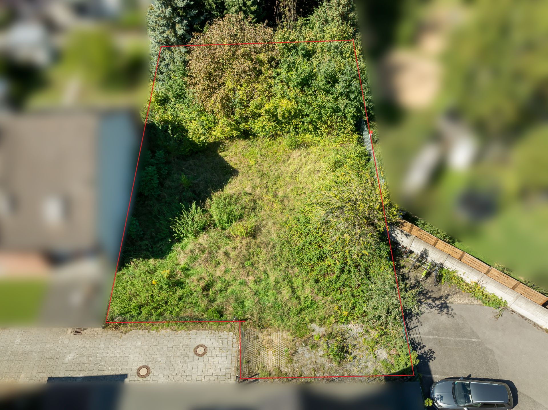 Luftaufnahme eines rechteckigen, unbebauten Grundstücks mit Gras und Büschen.