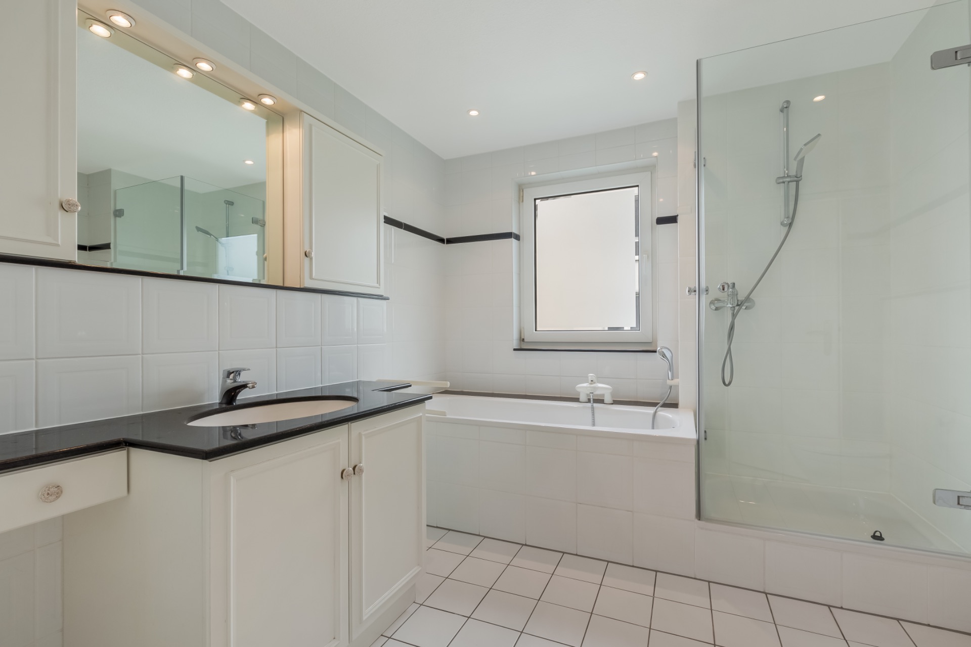 Modernes Badezimmer mit Dusche, Badewanne, Waschbecken und beleuchtetem Spiegel.