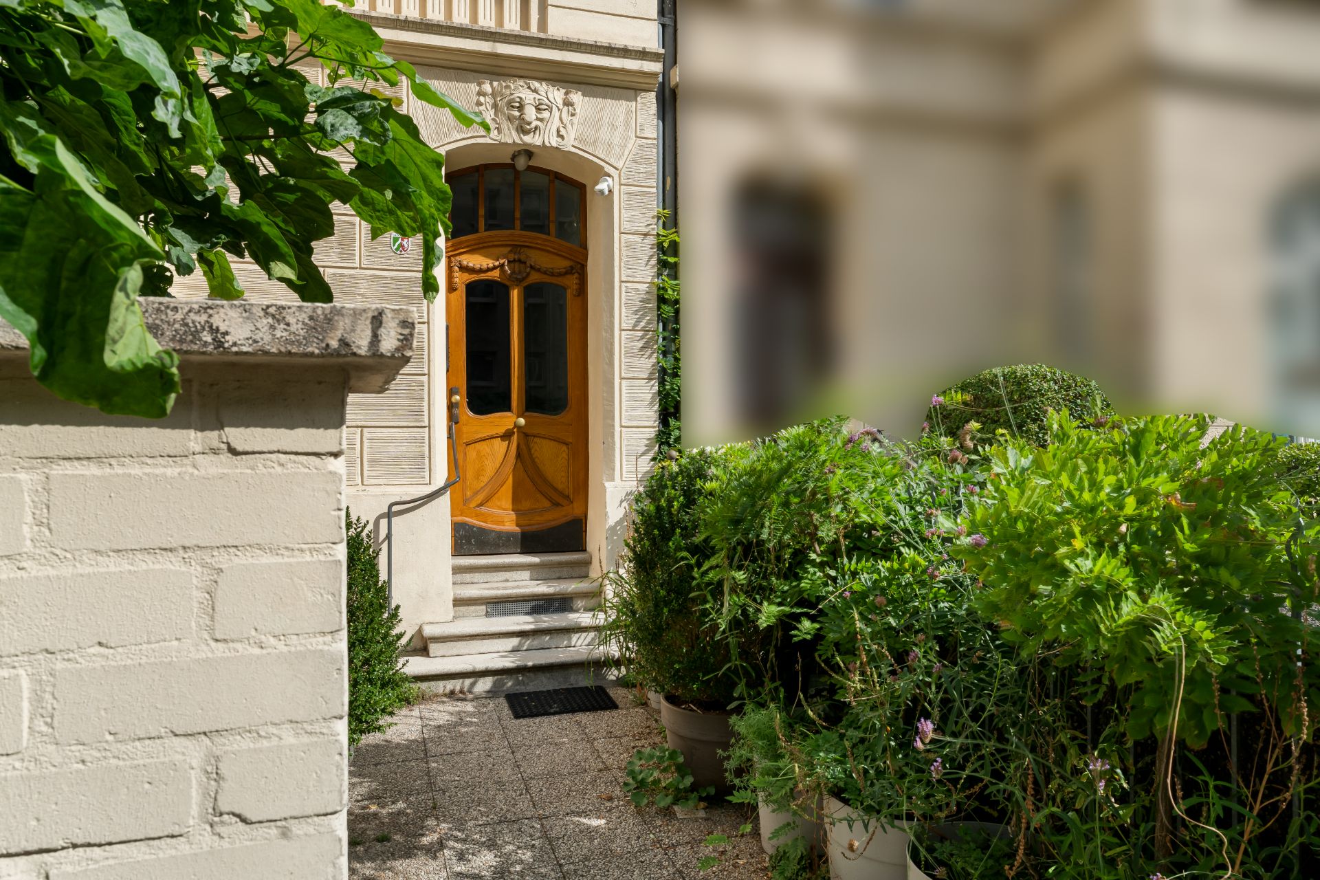 Eingangstür eines Wohnhauses mit Pflanzen und Treppe davor.
