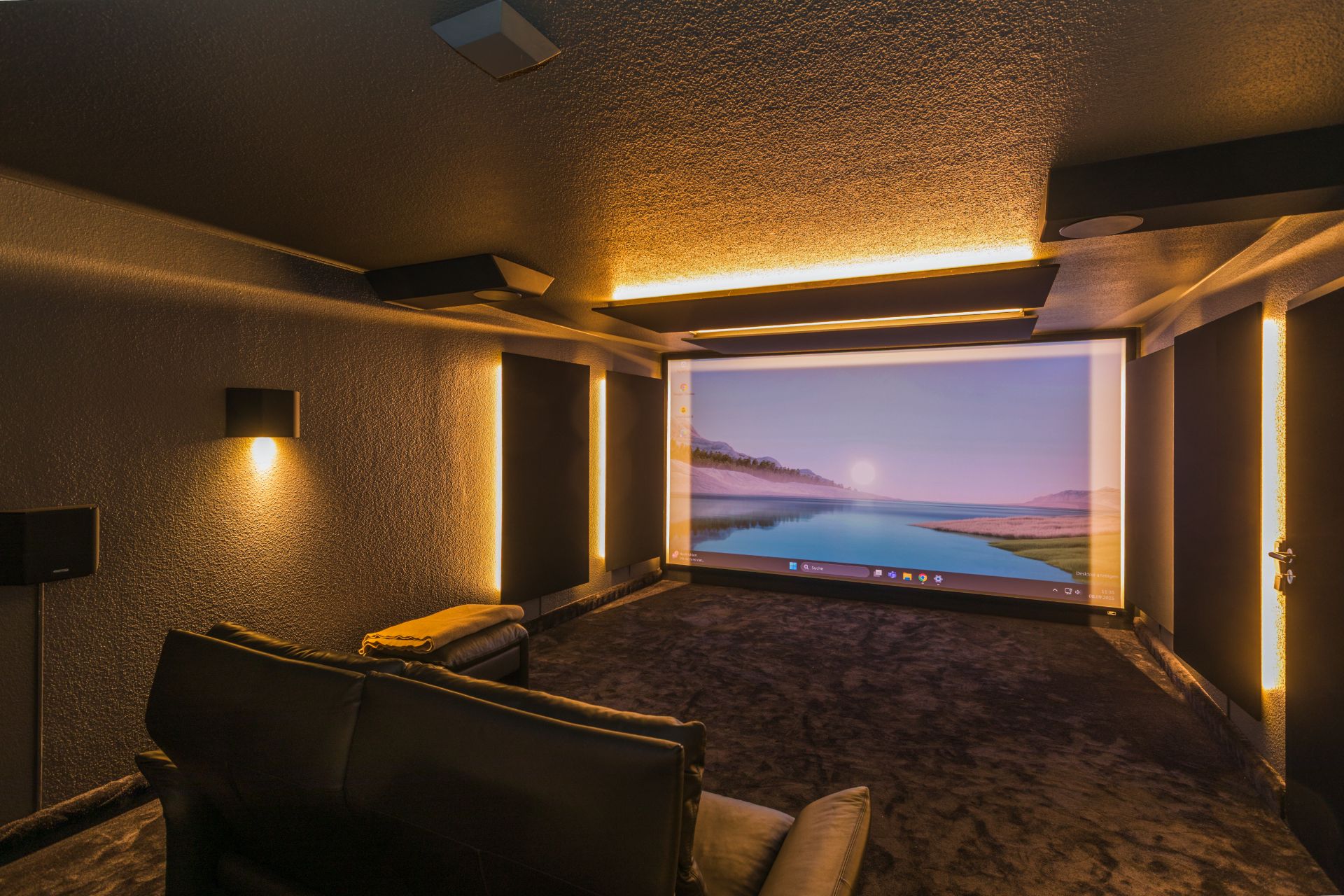 Heimkino mit großer Leinwand, zwei Sofas und stimmungsvoller Beleuchtung.