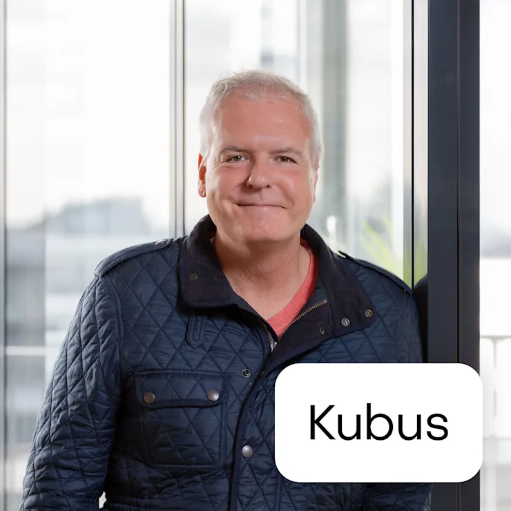 Ein Mann steht vor einer Glasscheibe in einem modernen Wohnraum.