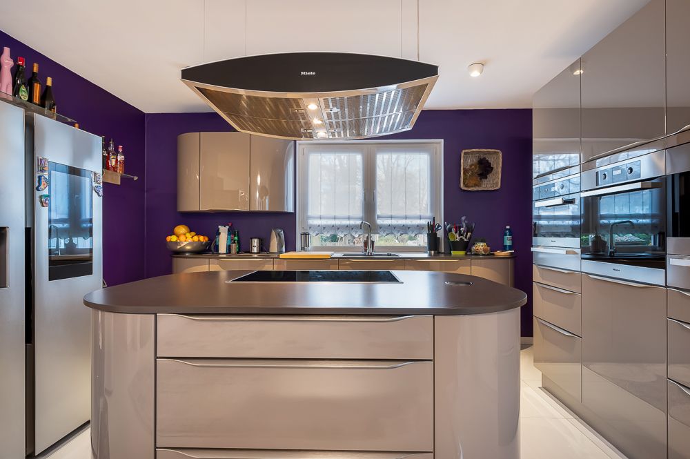 Moderne Küche mit lila Wänden, großem Kühlschrank, Kücheninsel und Fenster.