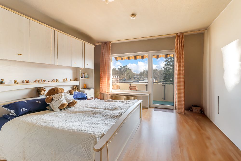 Helles Schlafzimmer mit Doppelbett, Einbauschränken und Zugang zu einem Balkon.