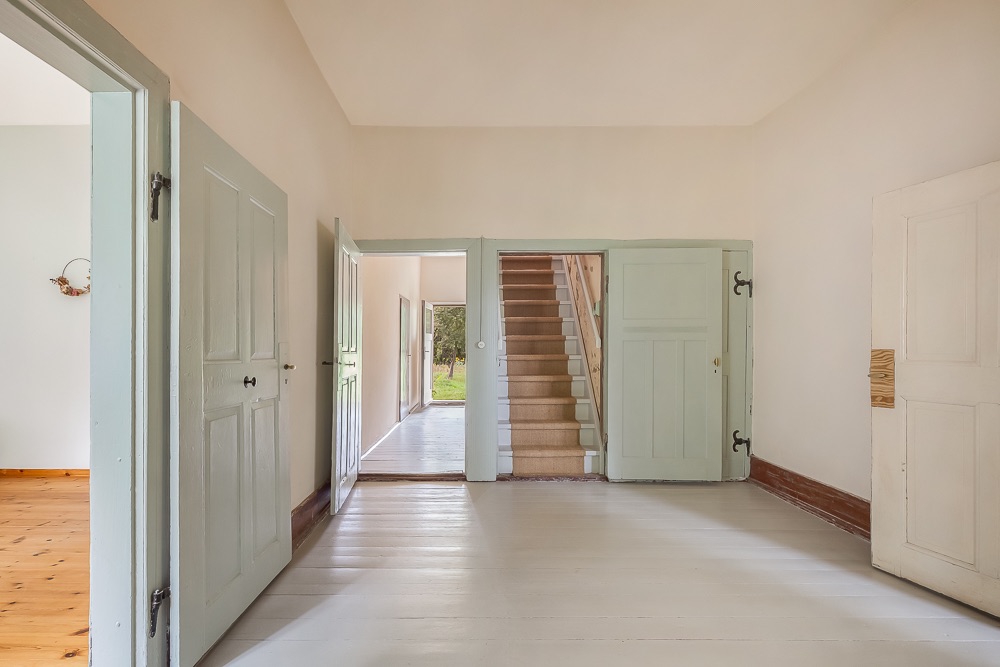 Heller Flur mit Holzboden, offenen Türen und Treppe in einem Wohnhaus.