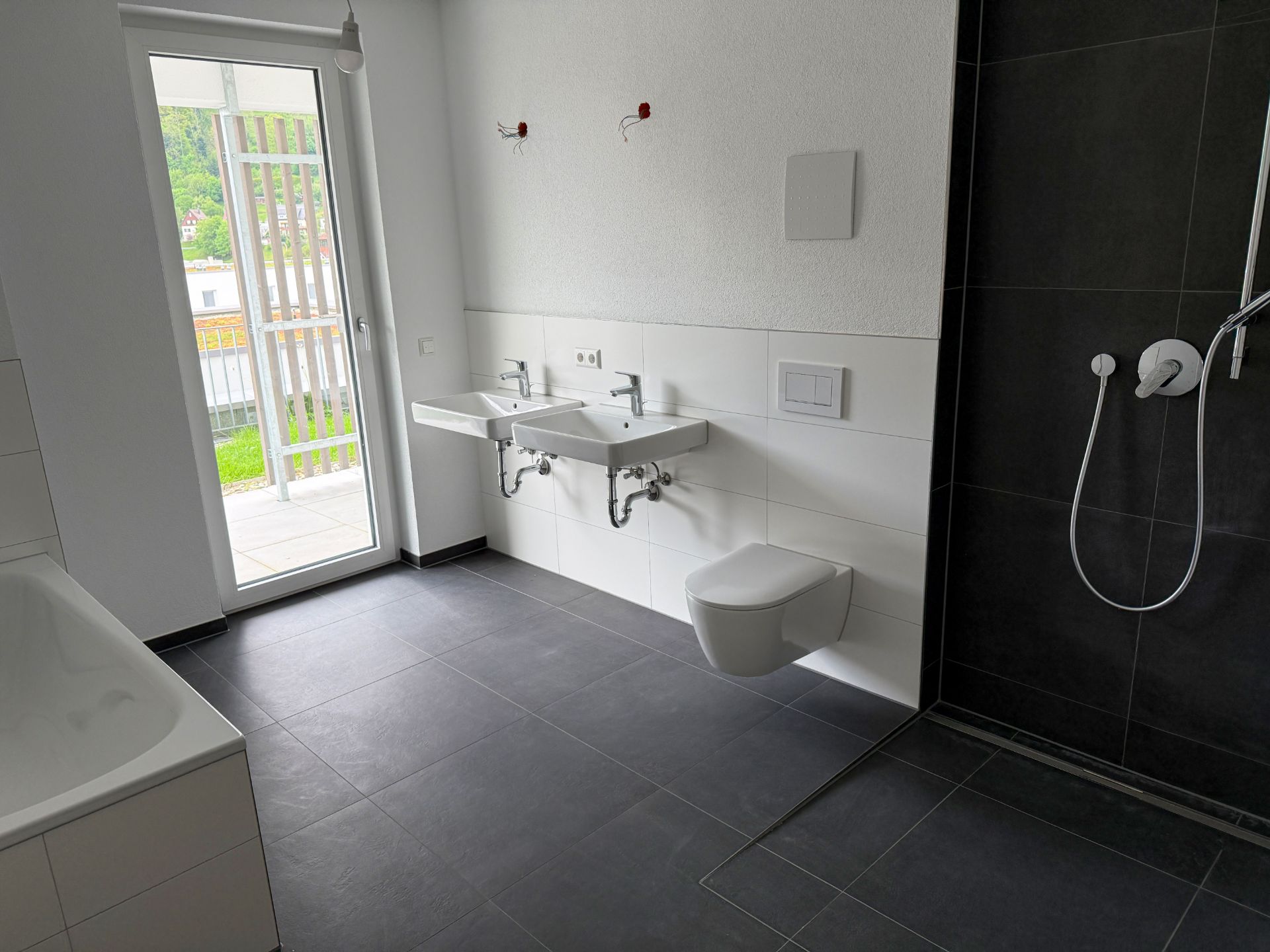 Modernes Badezimmer mit zwei Waschbecken, Dusche, Badewanne und Zugang zum Balkon.