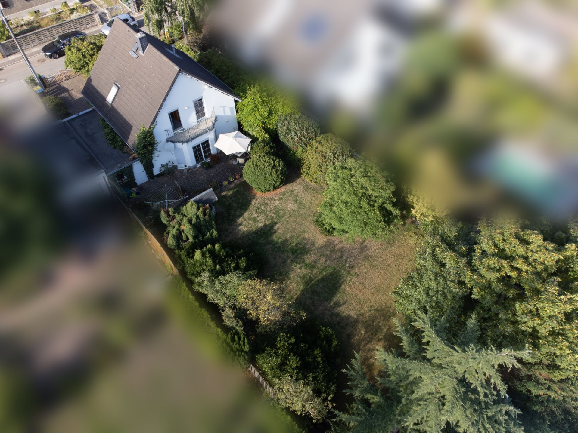Luftbild eines weißen Hauses mit Garten und Bäumen im Wohngebiet.
