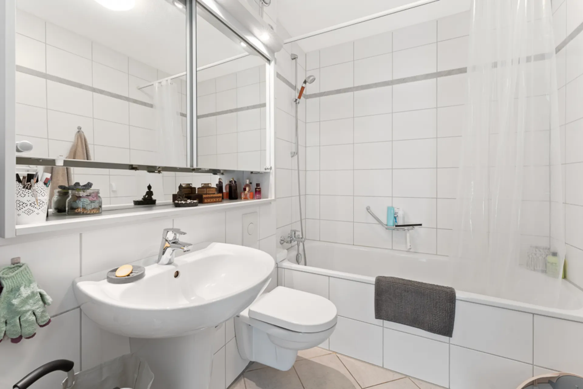 Modernes Badezimmer mit weiß gefliester Badewanne, Waschbecken, Spiegel und WC.