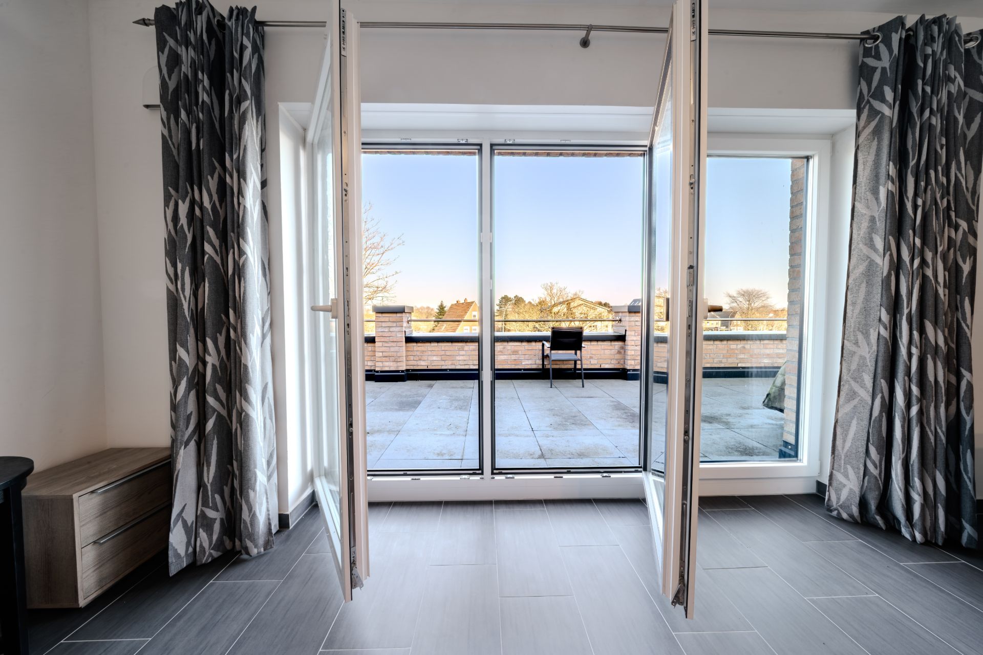 Große Glastüren führen von einem Raum zu einer Terrasse mit Ausblick ins Freie.