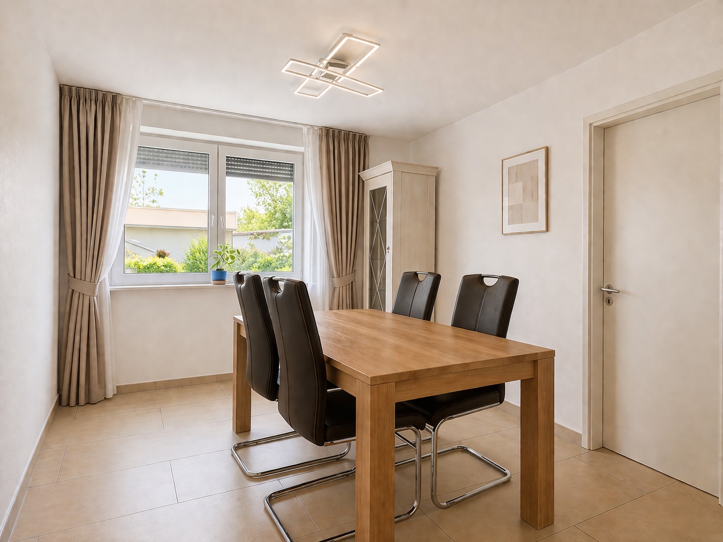 Esszimmer mit Holztisch, vier schwarzen Stühlen, Fenster mit Vorhängen und einem Schrank.
