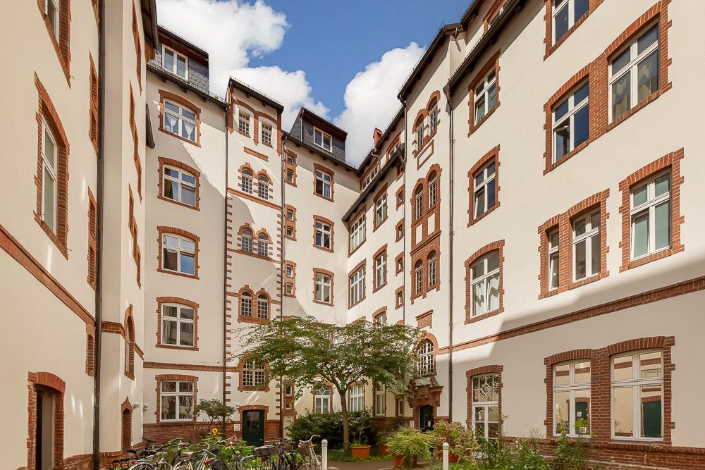 Innenhof eines Wohngebäudes mit Bäumen, Fahrrädern und vielen Fenstern.