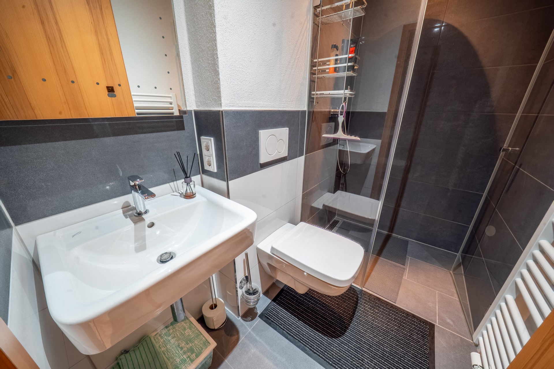Modernes Badezimmer mit Waschbecken, Wandtoilette und ebenerdiger Dusche.