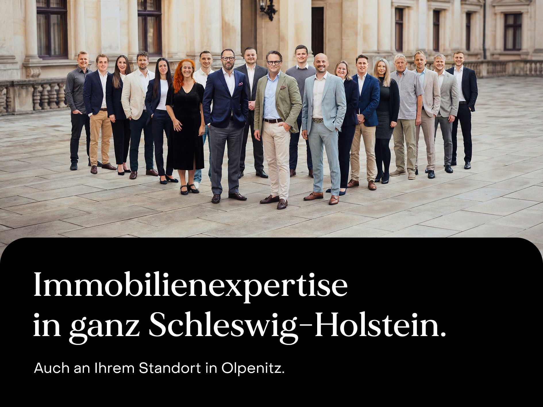 Eine Gruppe von 18 Personen steht im Freien vor einem historischen Gebäude.