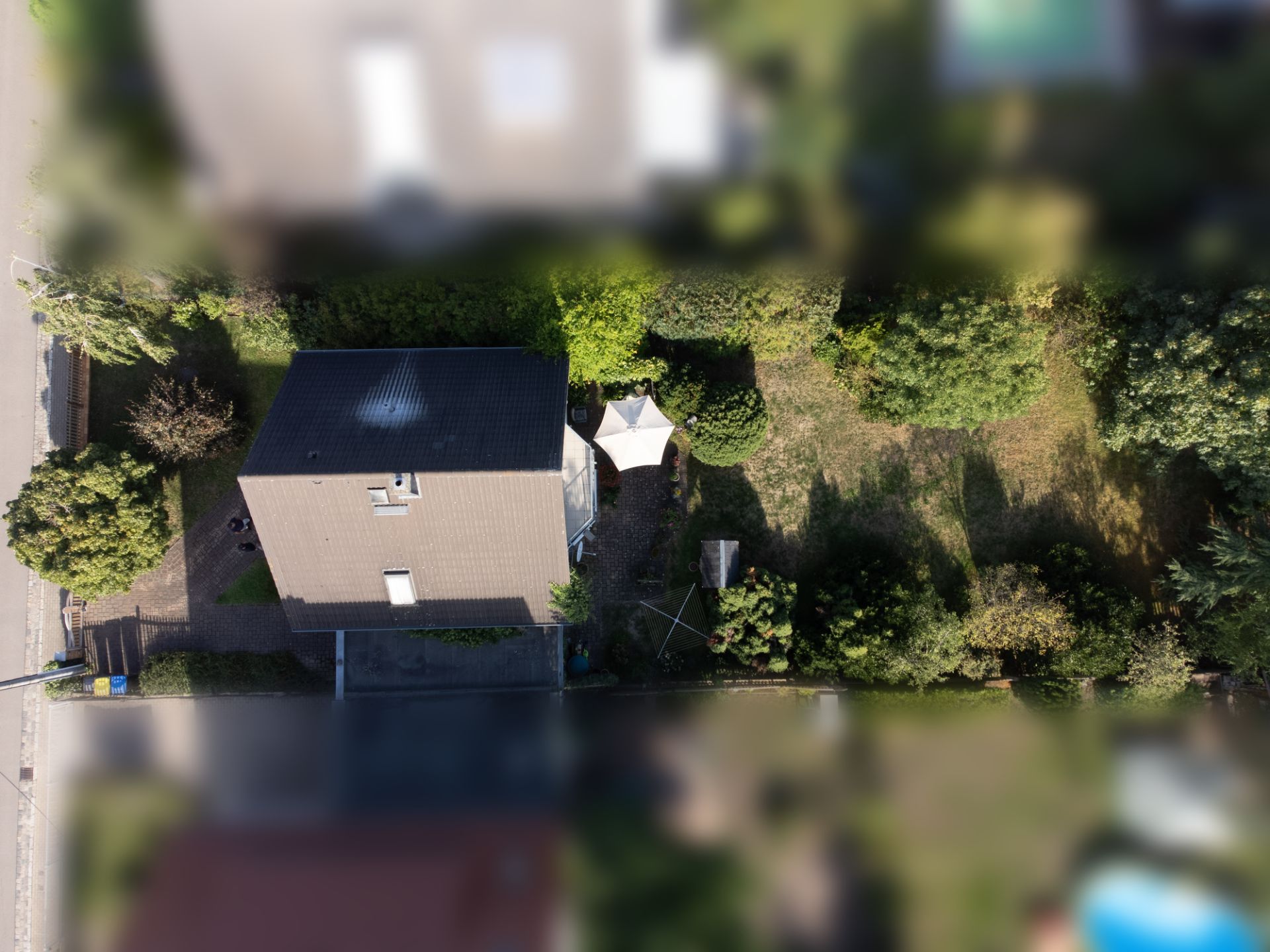 Luftaufnahme eines Einfamilienhauses mit Garten, Rasenfläche und Pavillon im Hinterhof.