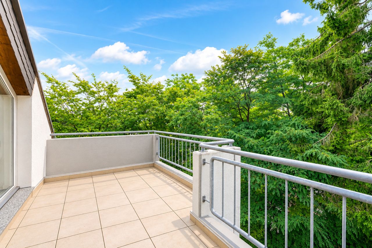 Geräumiger Balkon mit Fliesenboden und Blick auf grüne Bäume.