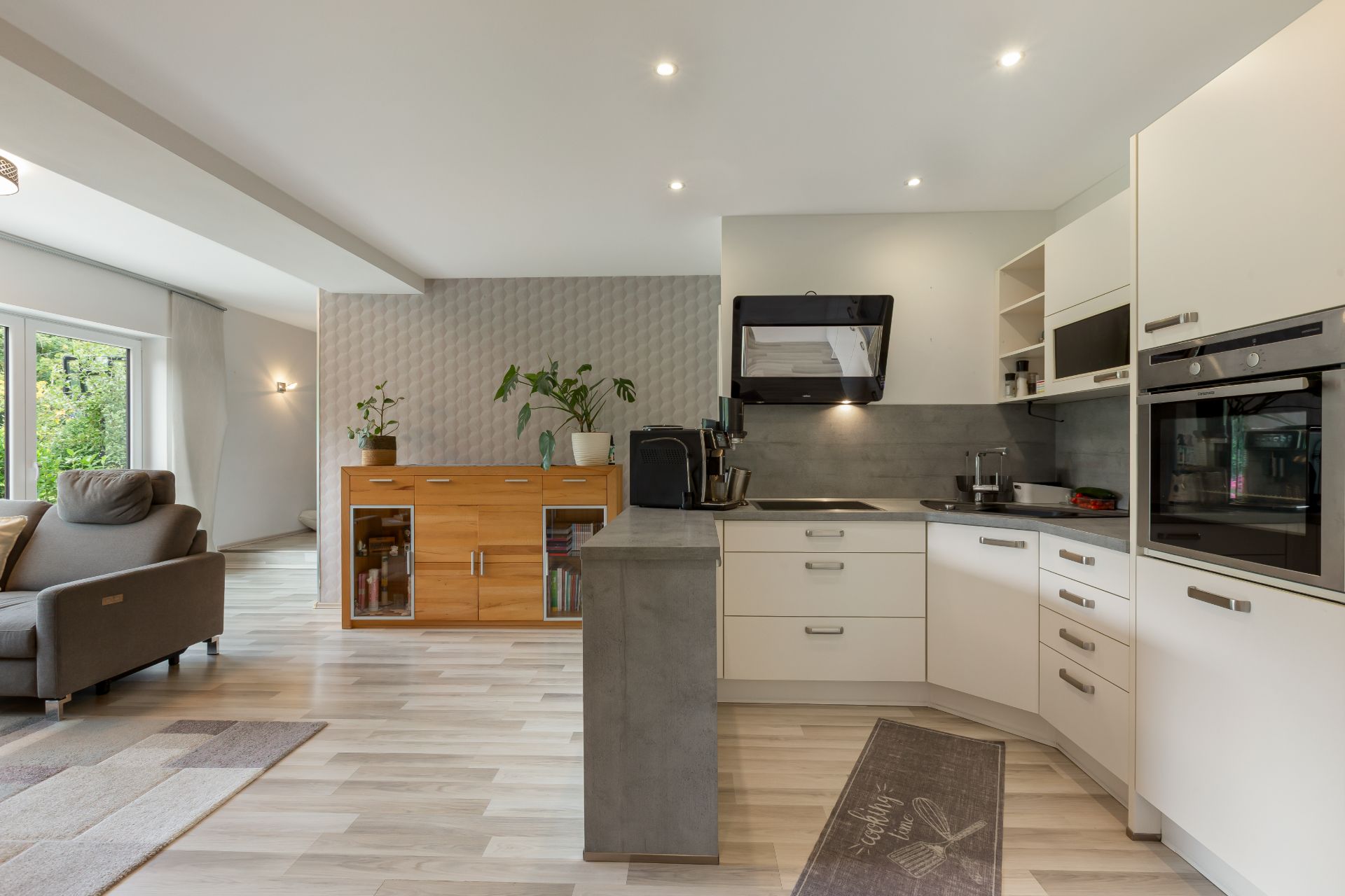 Moderne offene Küche mit weißen Schränken, Kücheninsel und angrenzendem Wohnzimmer.