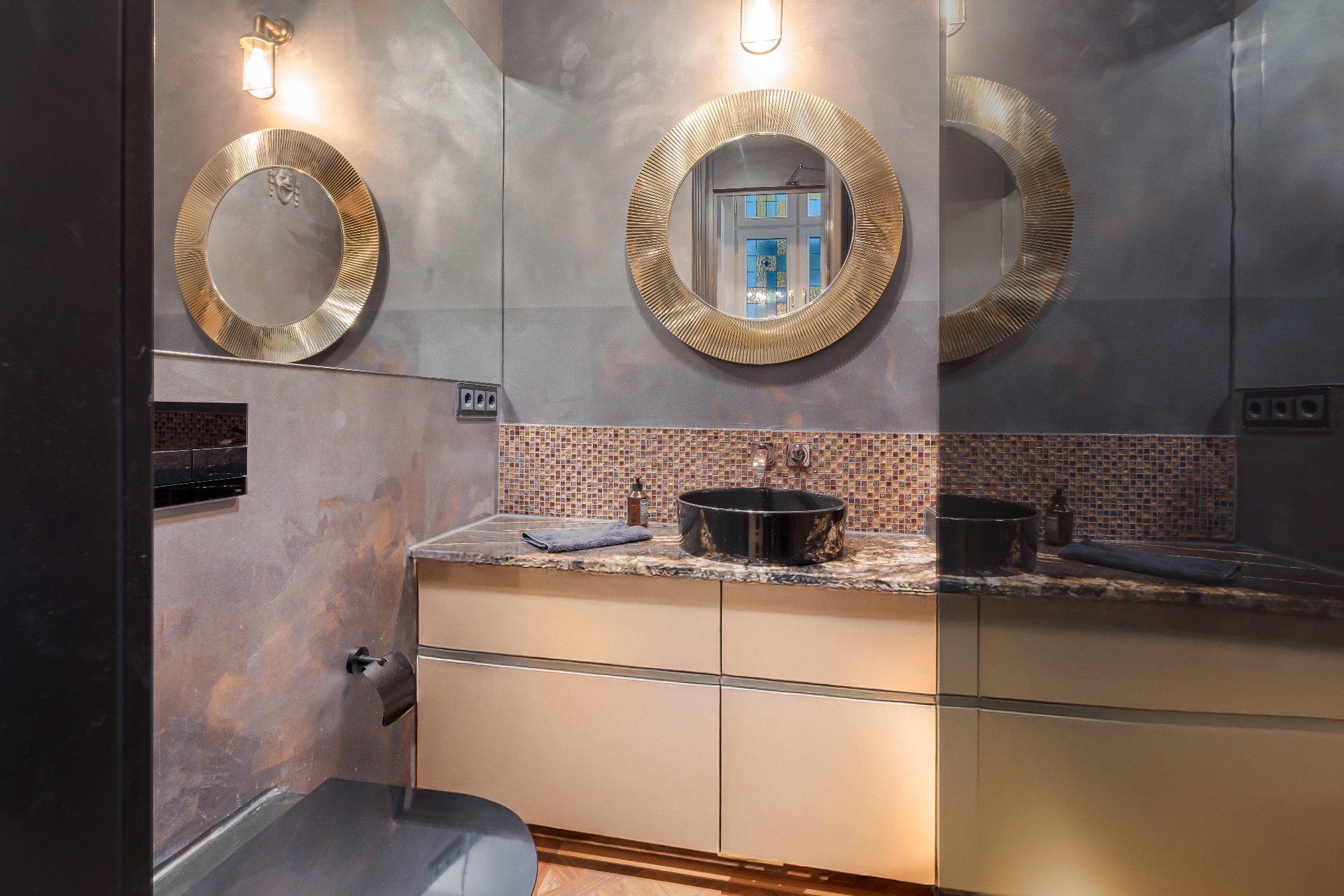 Modernes Badezimmer mit rundem Spiegel, Waschbecken und gemusterter Wandfliese.