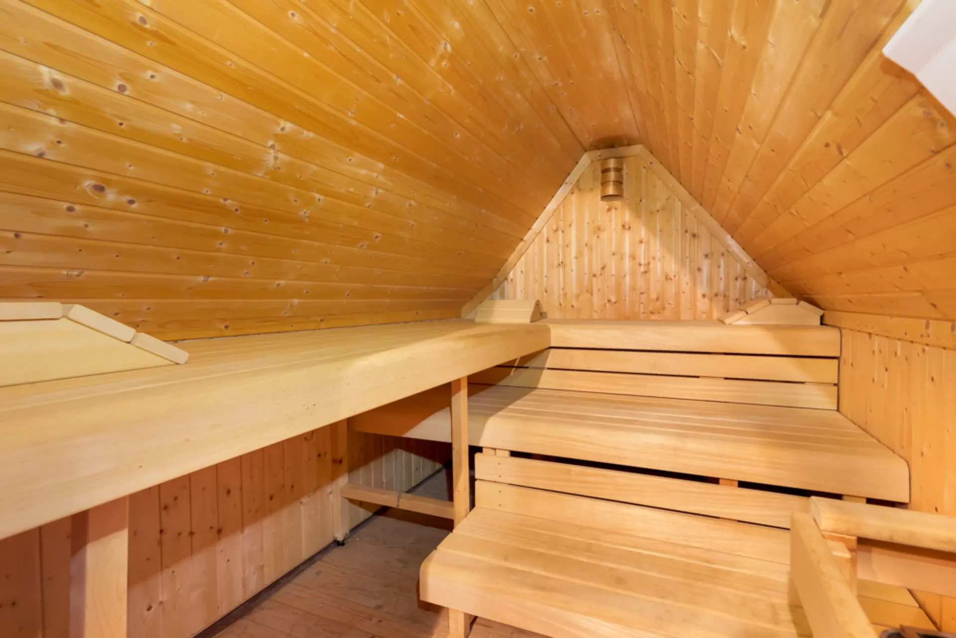 Holzsauna mit zwei Sitzbänken und abgeschrägter Decke.