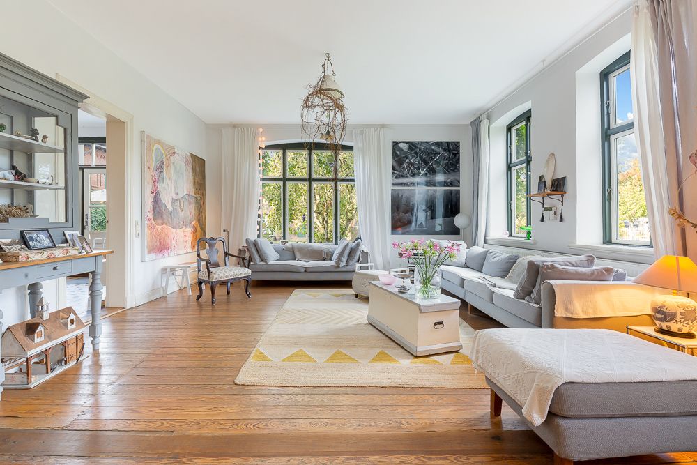 Helles Wohnzimmer mit zwei Sofas, Holzfußboden, großen Fenstern und dekorativem Couchtisch.