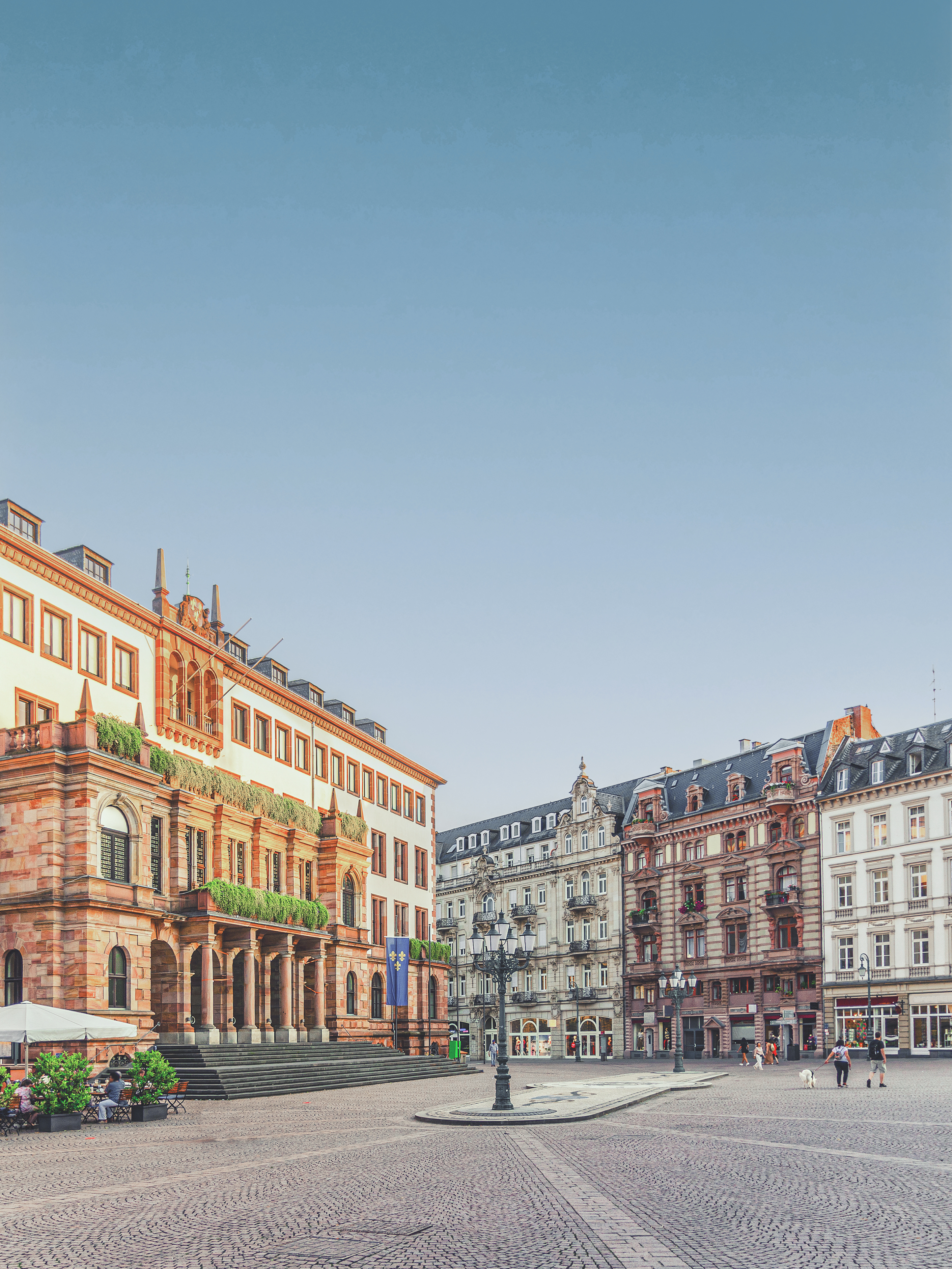 Historische Wohngebäude an einem großen, gepflasterten Platz bei Tageslicht.