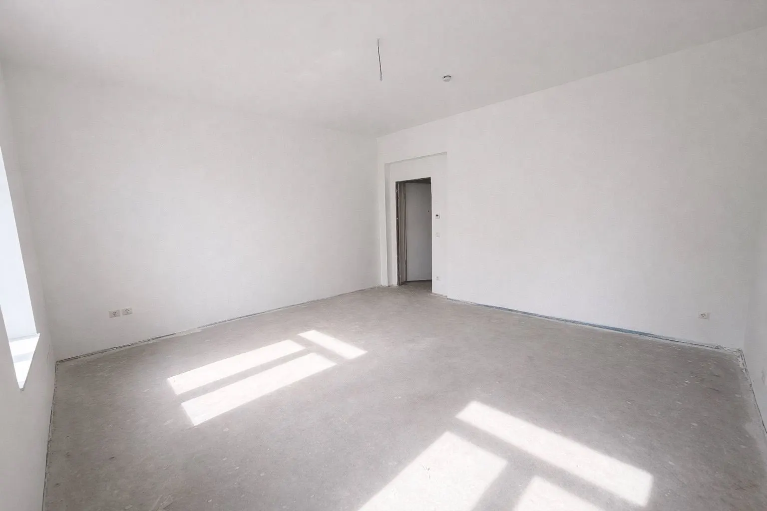 Leerer, heller Raum mit weißen Wänden, Fenster und Tür zu einem anderen Zimmer.