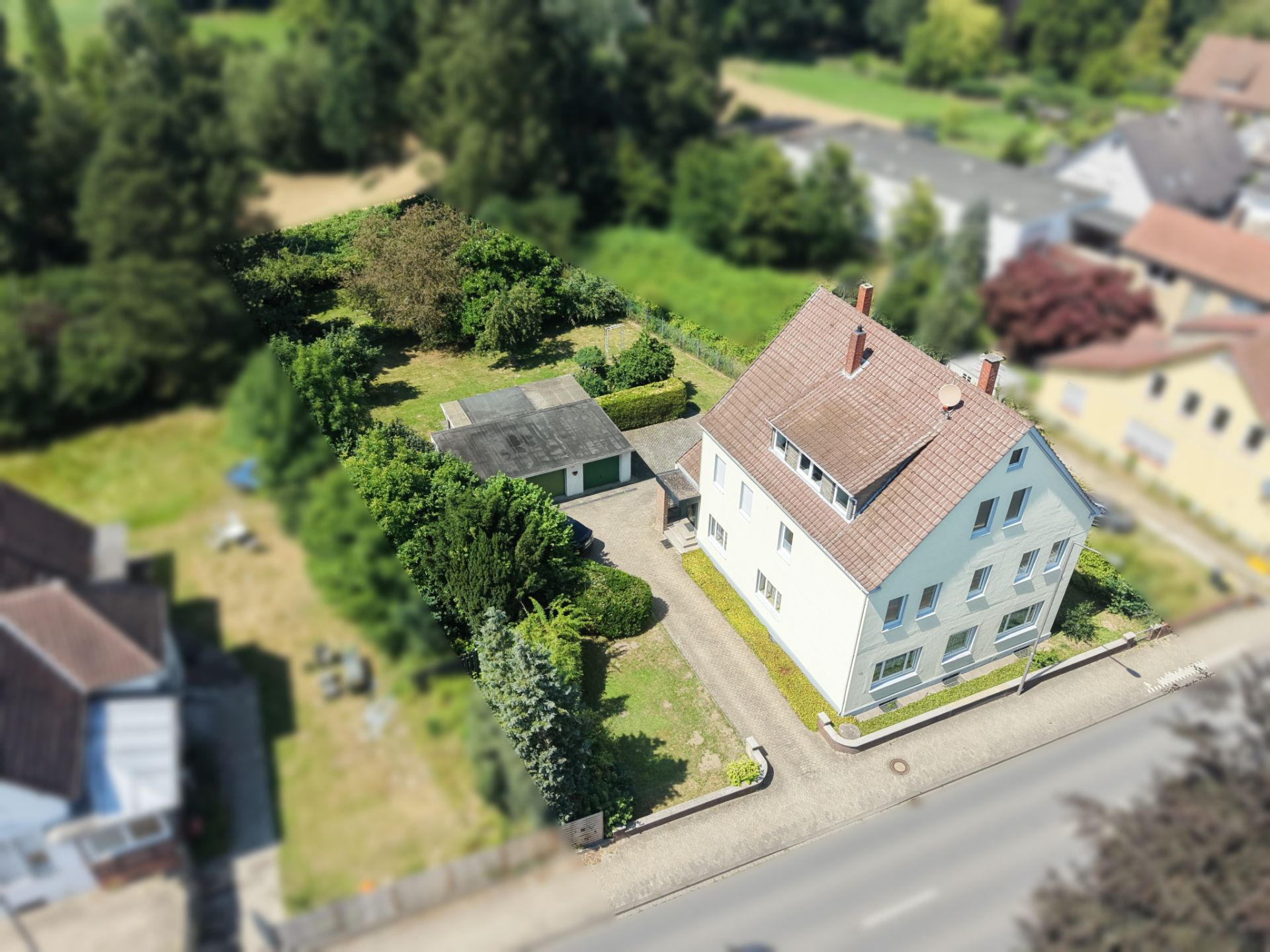 Luftaufnahme eines weißen Wohnhauses mit Nebengebäude und Garten.