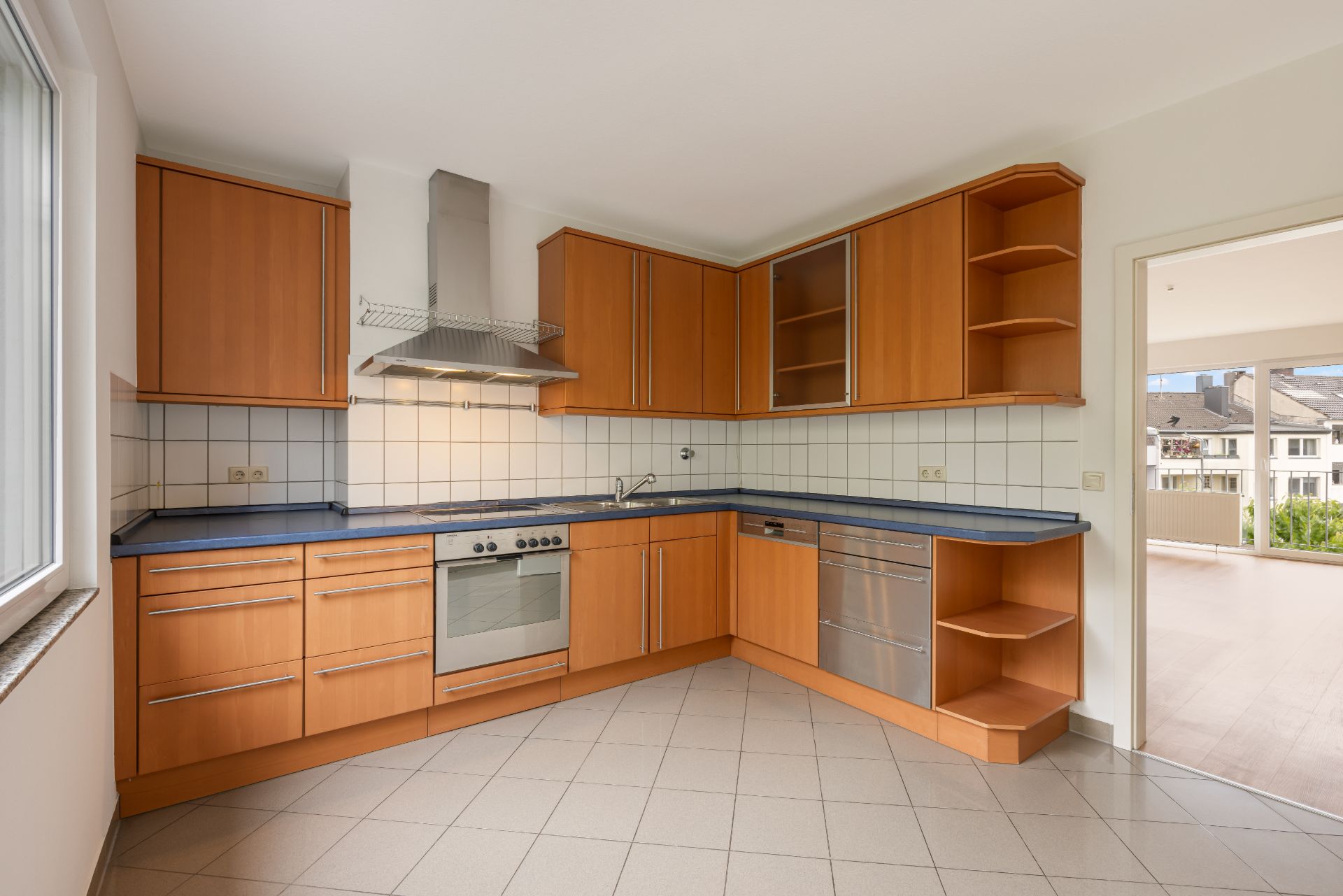 Moderne Einbauküche mit Holzmöbeln, Edelstahlherd und Spülmaschine, Fenster links.
