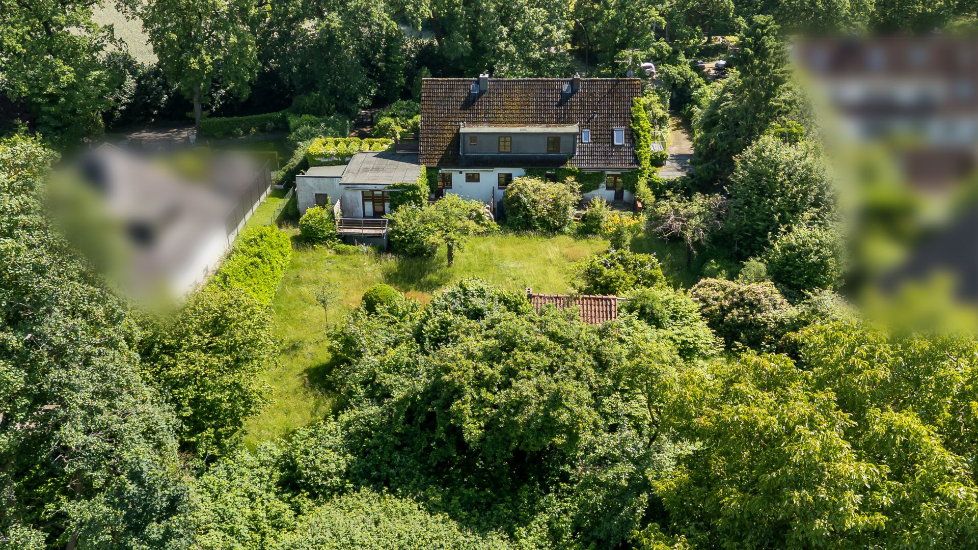 Luftaufnahme eines Wohnhauses mit großem Garten und viel umgebender Vegetation.