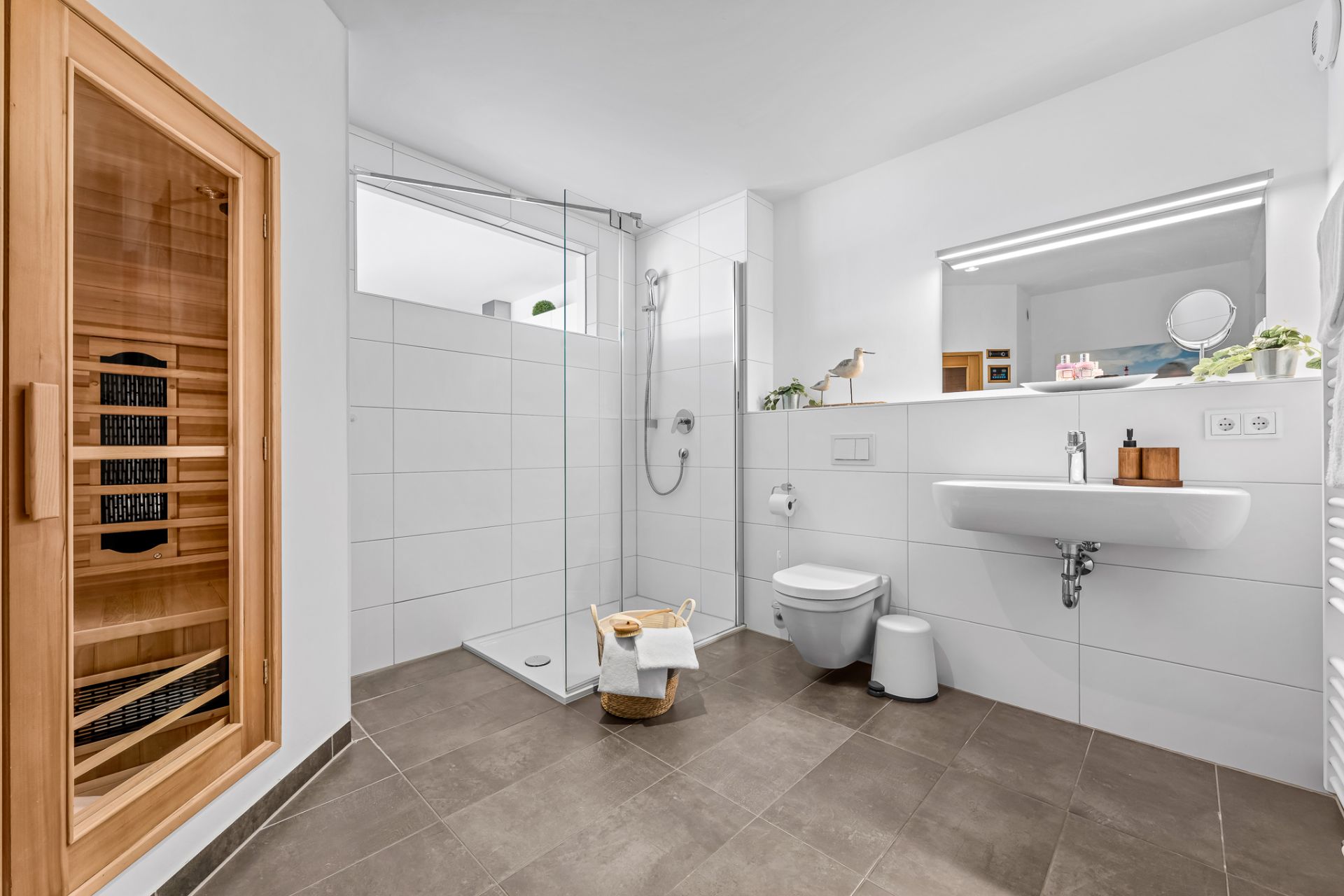Modernes Badezimmer mit Sauna, begehbarer Dusche, WC und Waschbecken mit Spiegel.